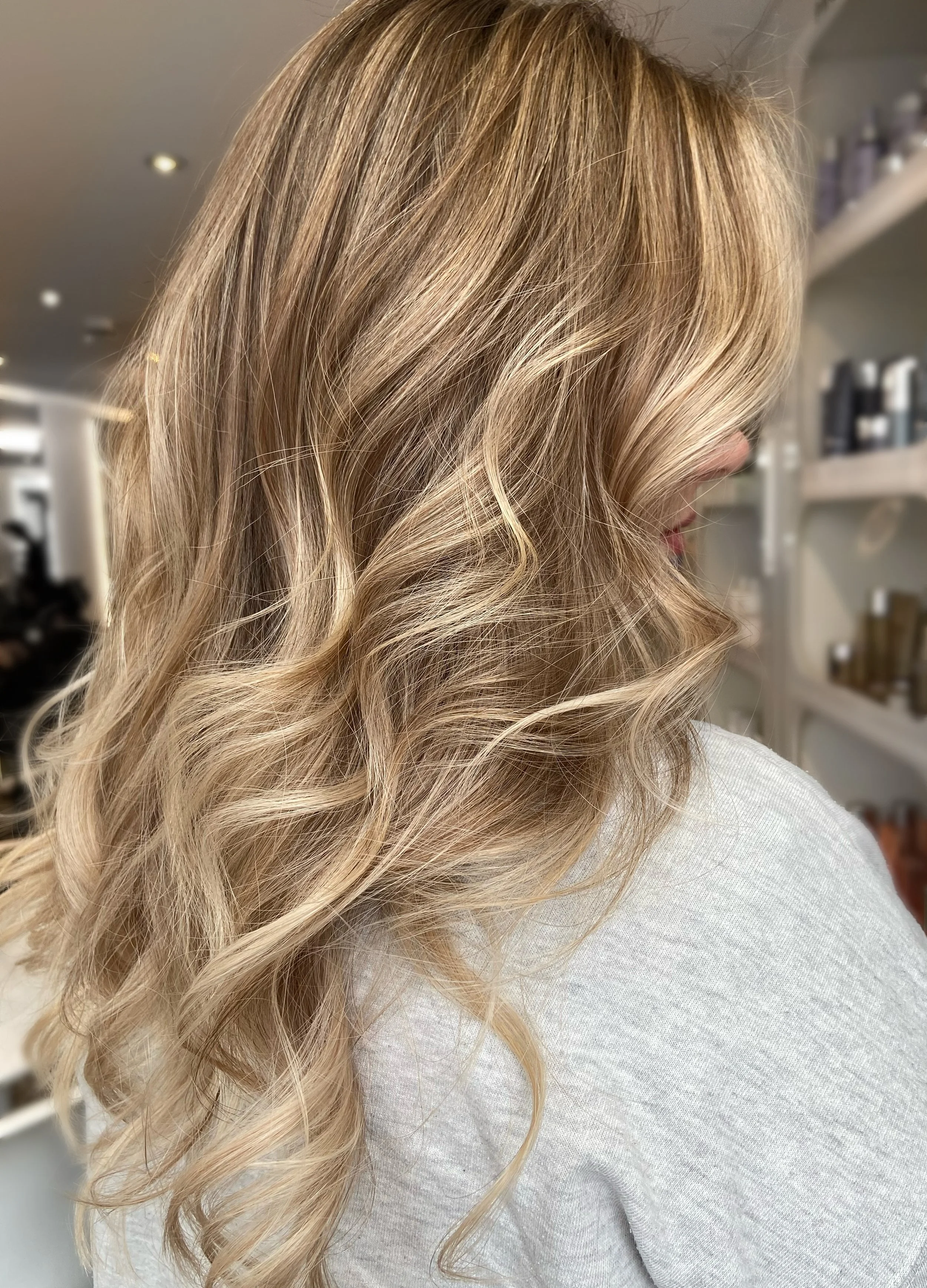 Close-up of a woman's blonde, wavy hair with honey and platinum highlights.
