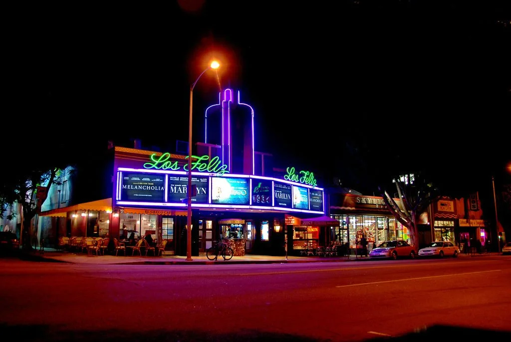 Night view of the Los Feliz 3 with parked cars and bicycles outside.