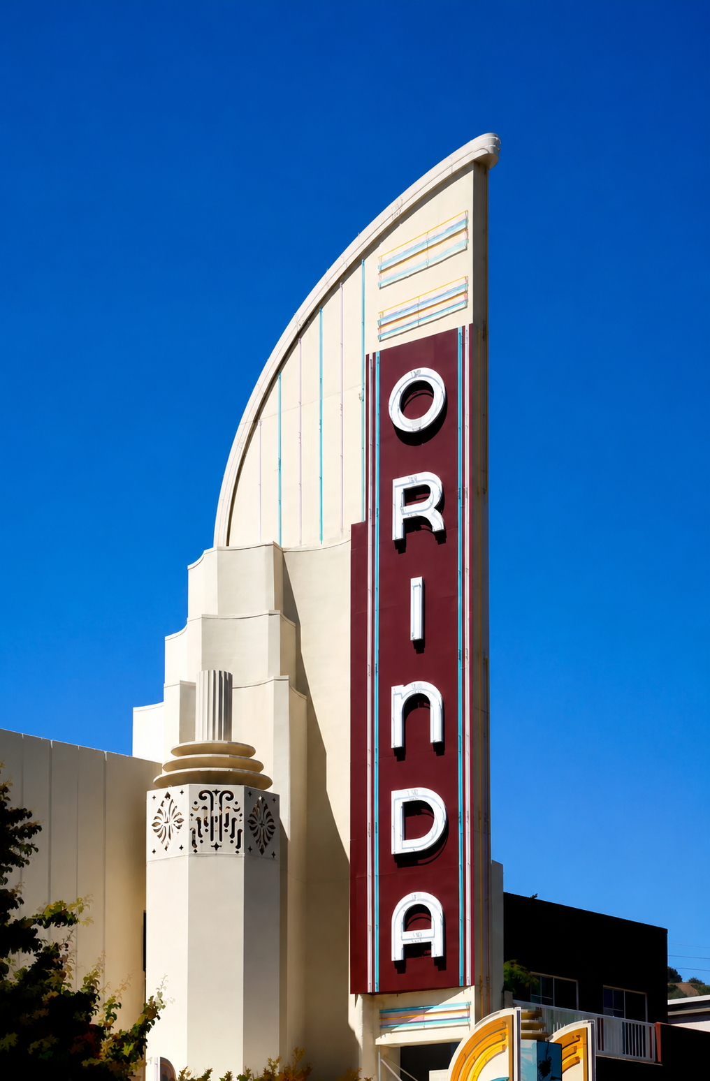 Art Deco style theater marquee of the Orinda against a deep blue sky.
