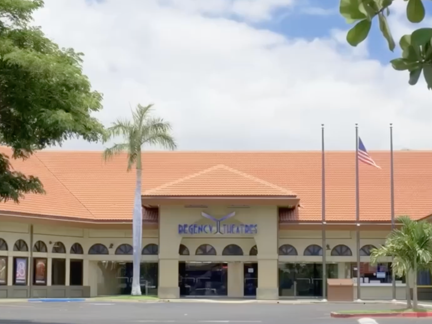 The facade of Regency Theatres with a yellow wall and a large sign, featuring a stylized 'Y' at the top of the sign, and a red-tiled roof. In Kihei, Hawaii.