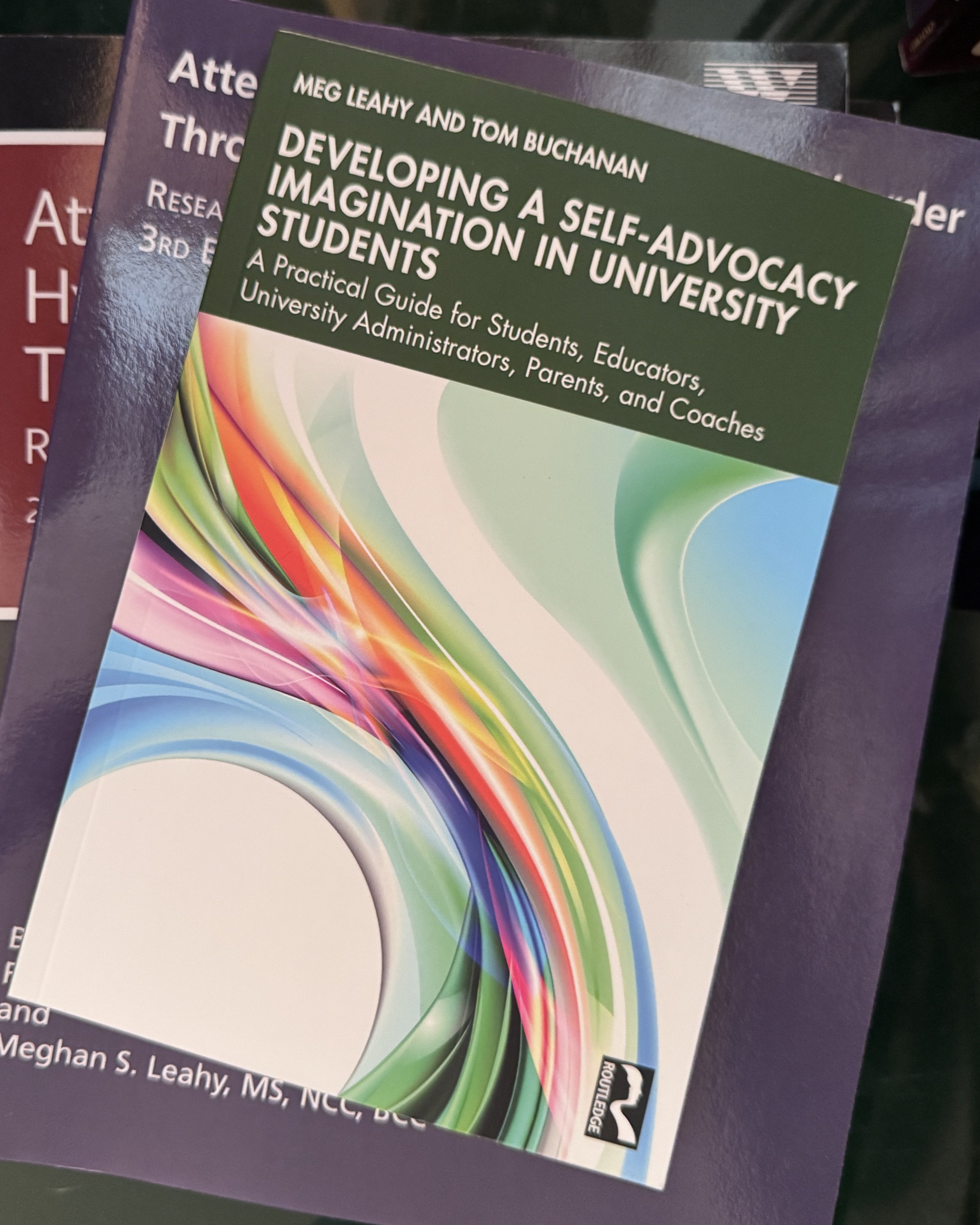 A stack of academic textbooks with colorful, abstract cover designs on a dark surface.