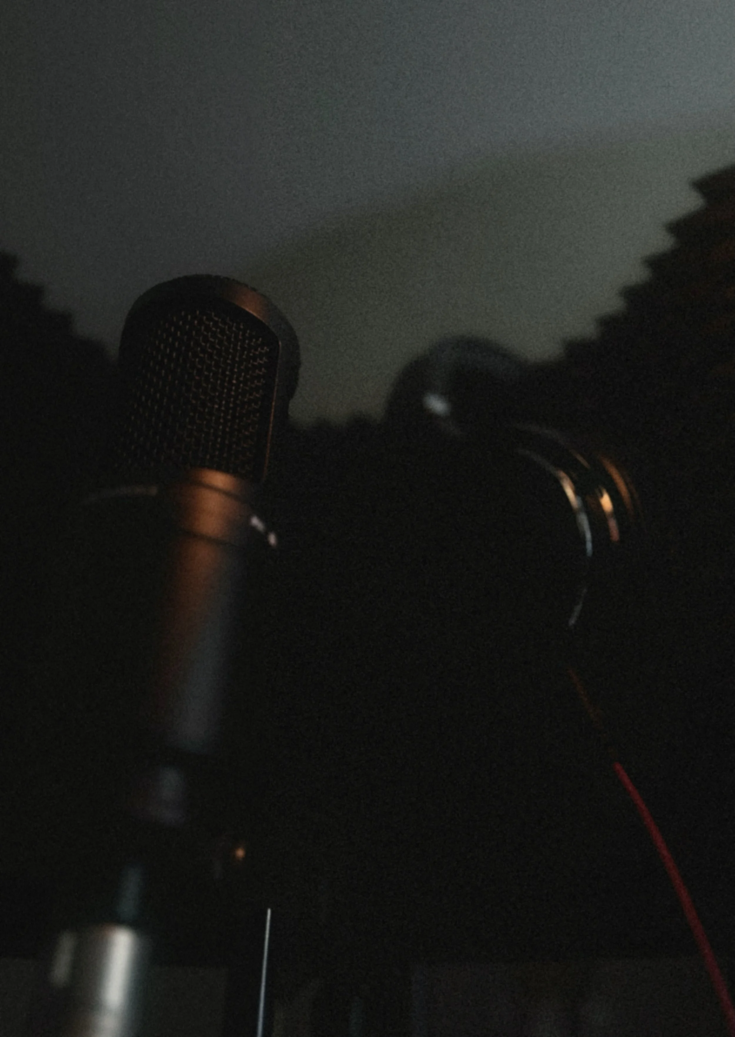 A close-up of a microphone with a dark background, possibly in a recording studio or stage.