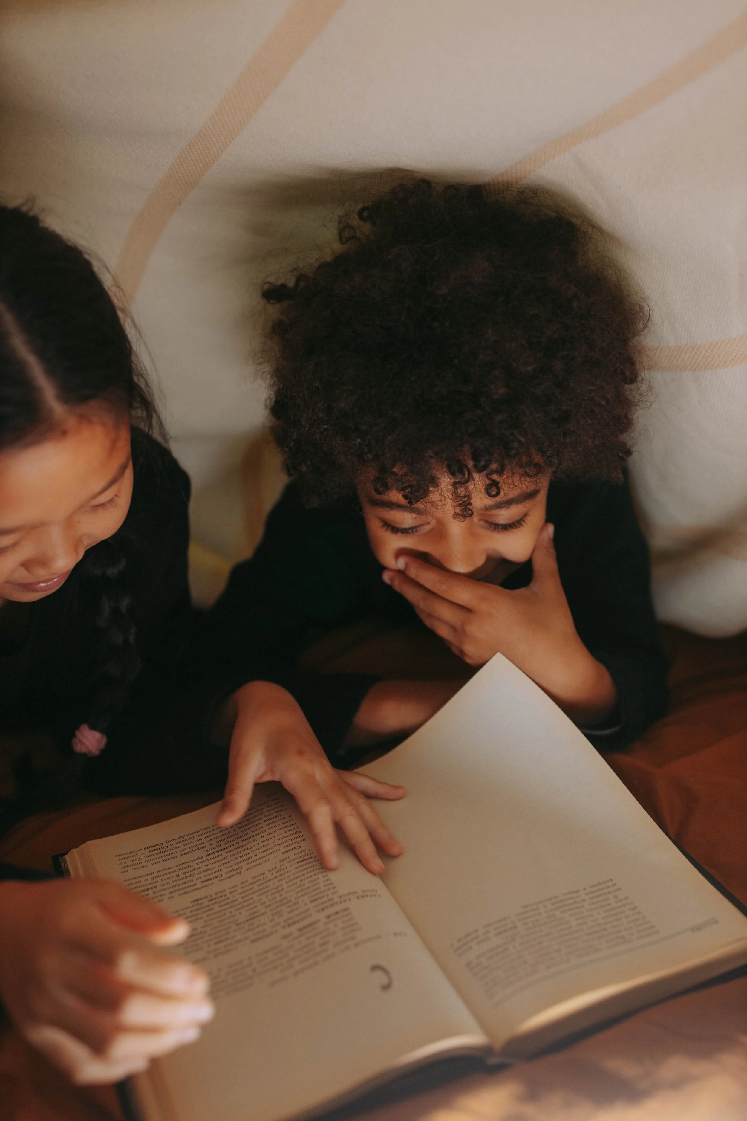 Two children reading a book together, one girl and one boy.