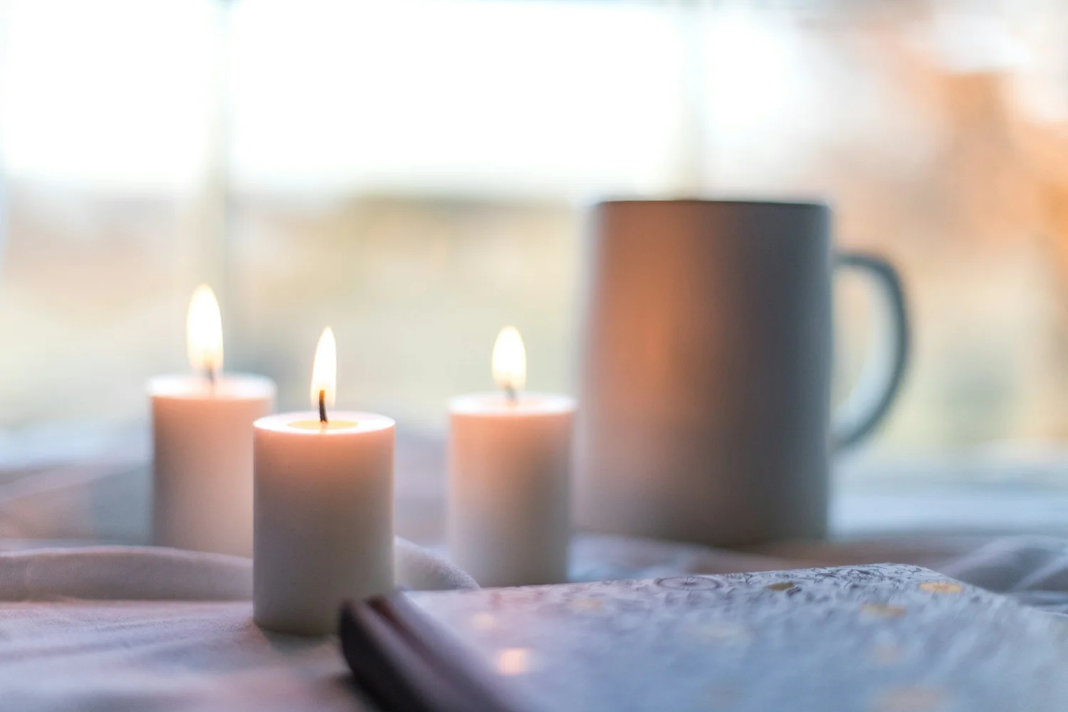 Candles and a mug by a sunlit window