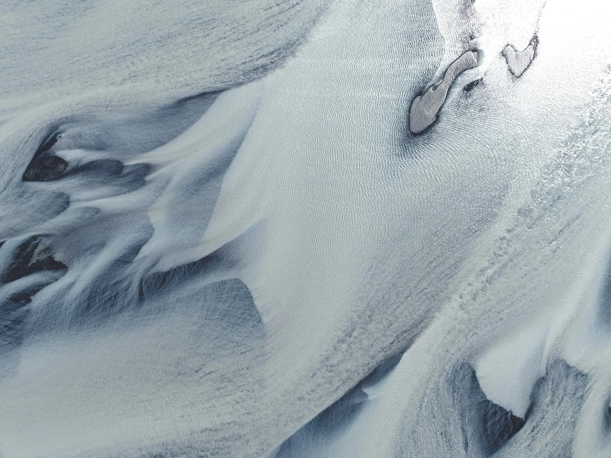 Close aerial view of smooth glacier ice and dark exposed areas in Iceland