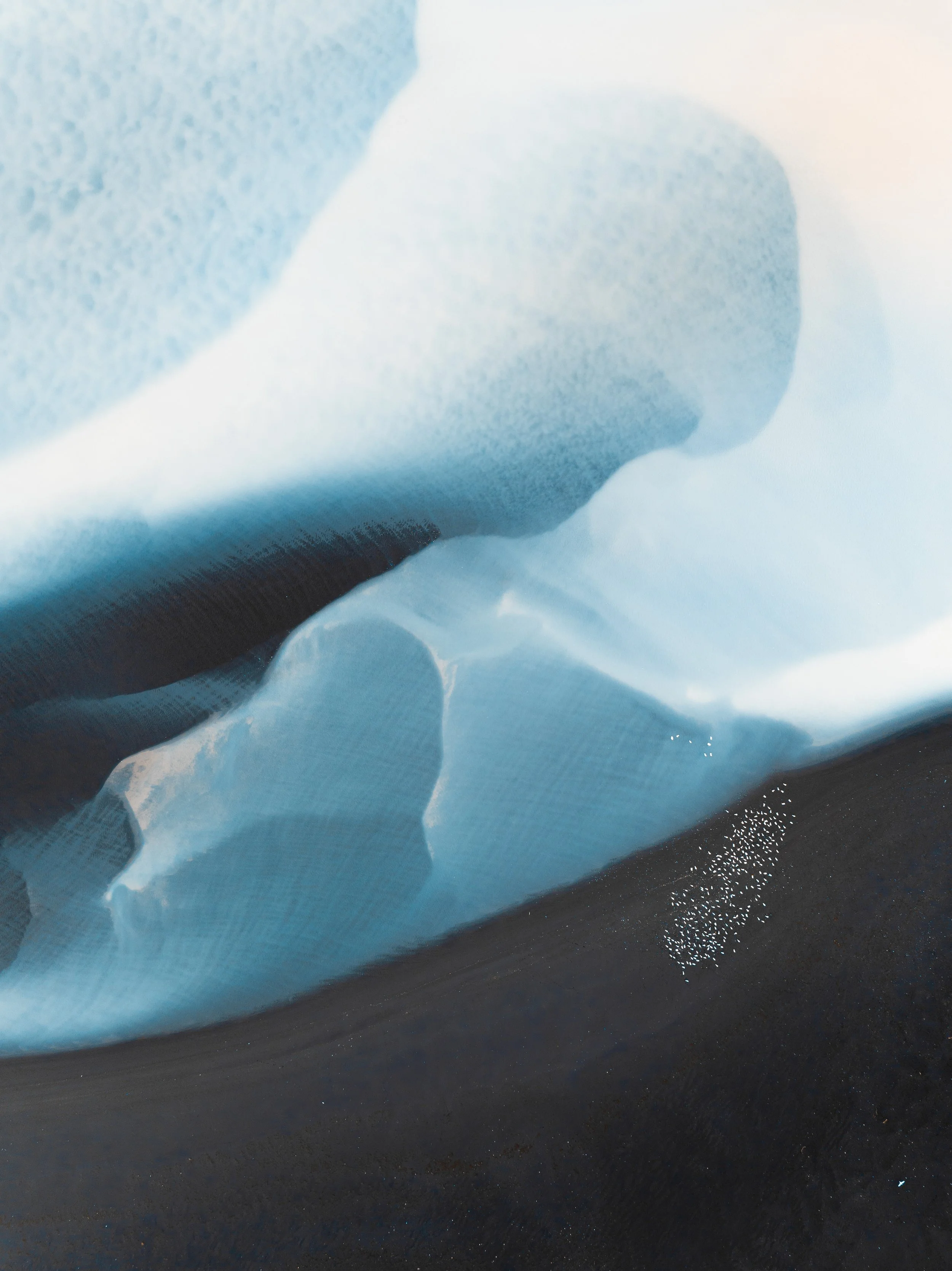 Aerial view of pale glacial sediments forming flowing patterns across the Icelandic landscape