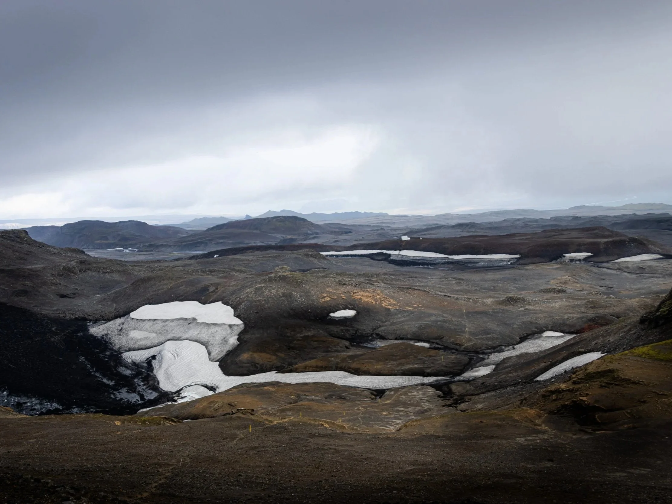 Remote volcanic landscape at Fimmvörðuháls in the Icelandic Highlands with patches of snow and dark mountains