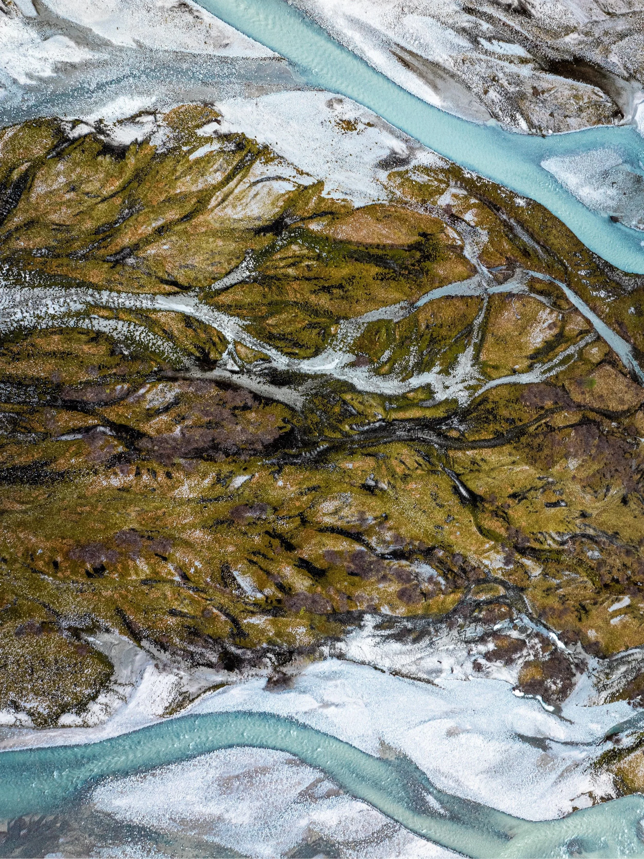 Aerial view of a turquoise glacial river flowing through a rugged landscape in Norway