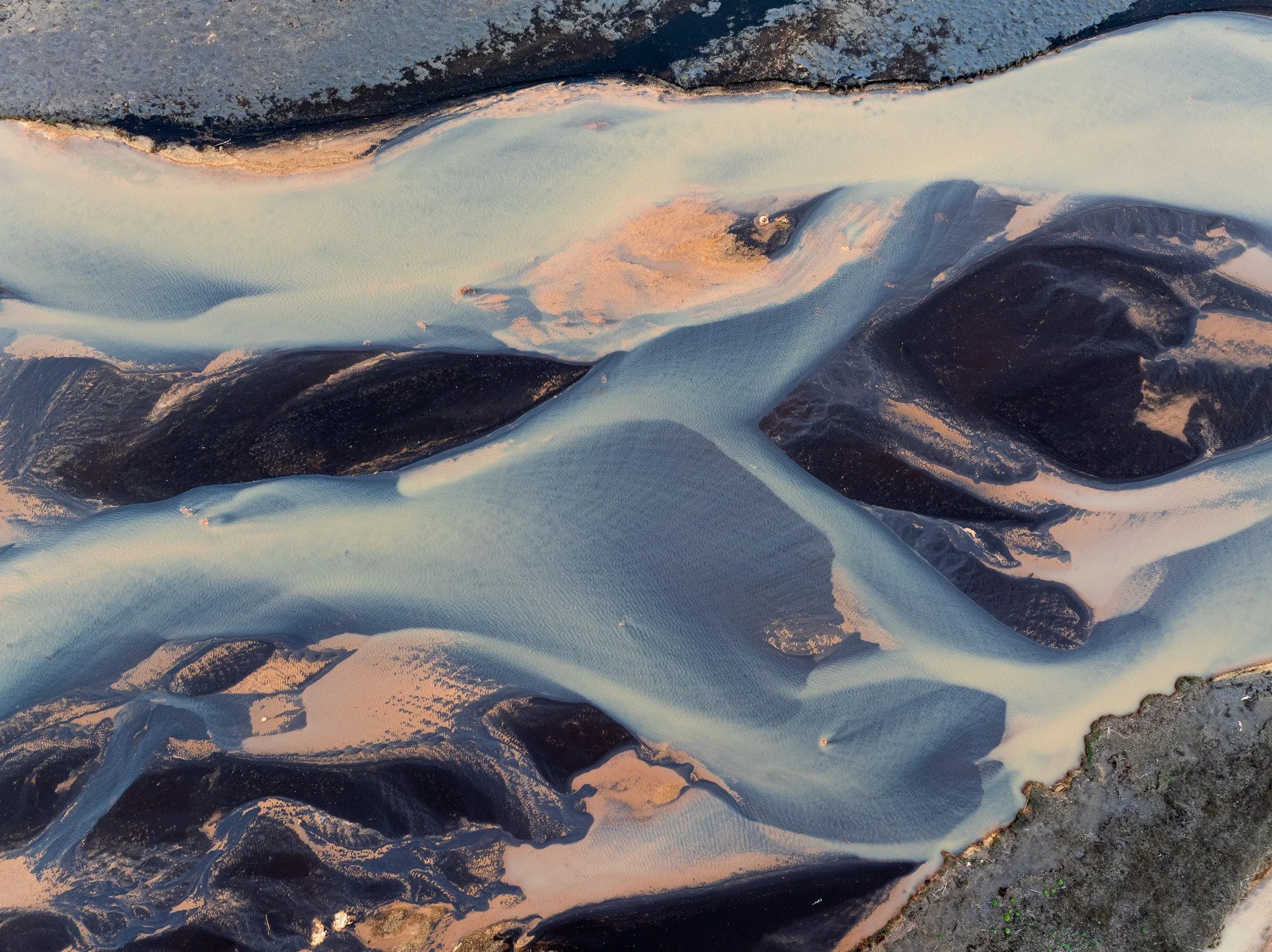 Aerial view of a braided glacial river flowing through Iceland's volcanic landscape