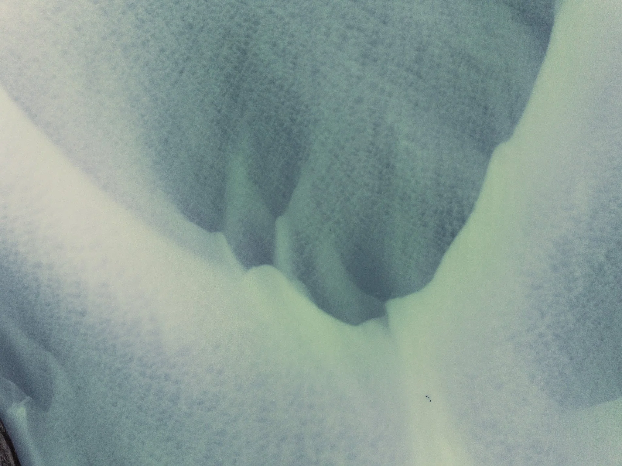 Aerial view of pale glacial sediments forming flowing patterns in Iceland