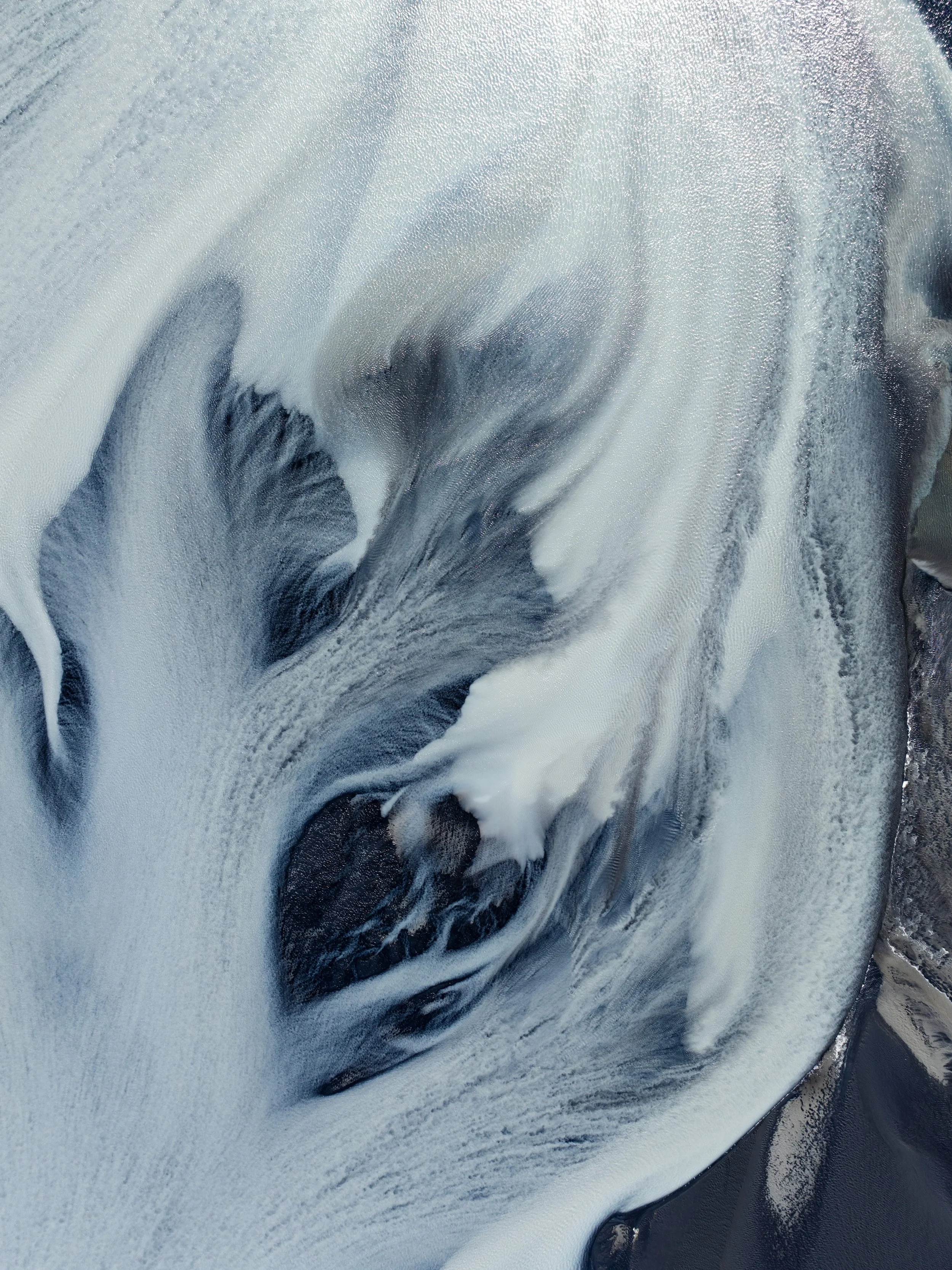 Aerial view of pale glacial sediments and flowing patterns across the Icelandic landscape