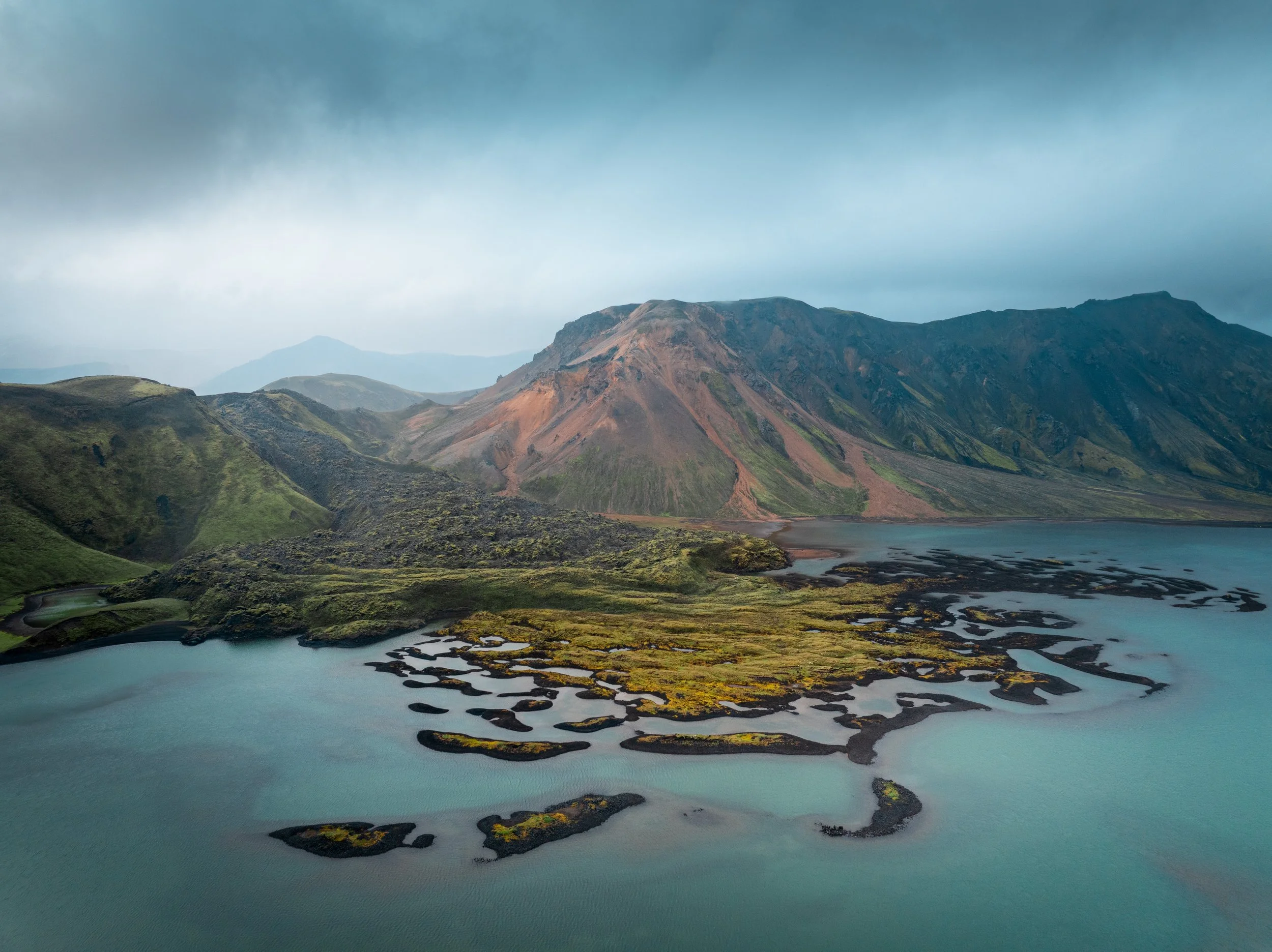 Aerial view of Námsárhraun volcanic landscape with turquoise water and rugged mountains in the Icelandic Highlands