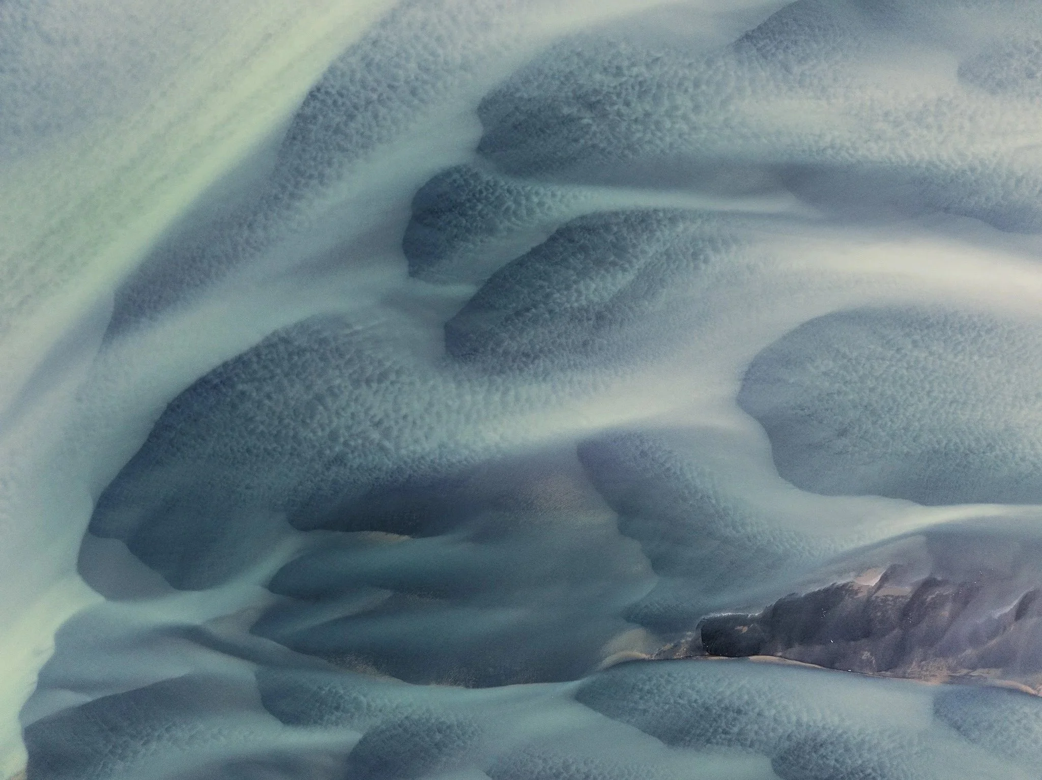 Aerial view of glacial sediments forming intricate natural patterns across the Icelandic landscape
