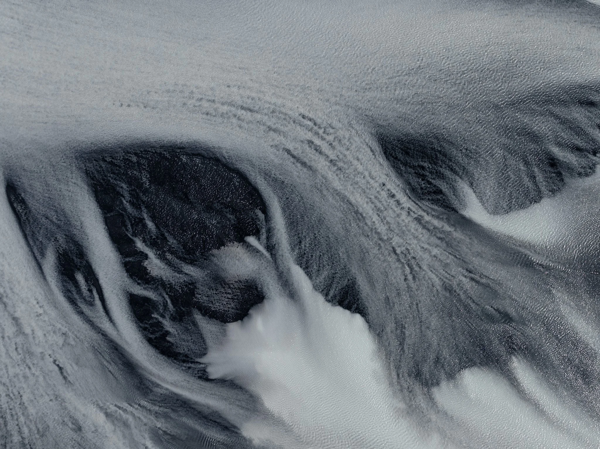 Aerial view of a braided glacial river flowing through the black volcanic landscape of Iceland