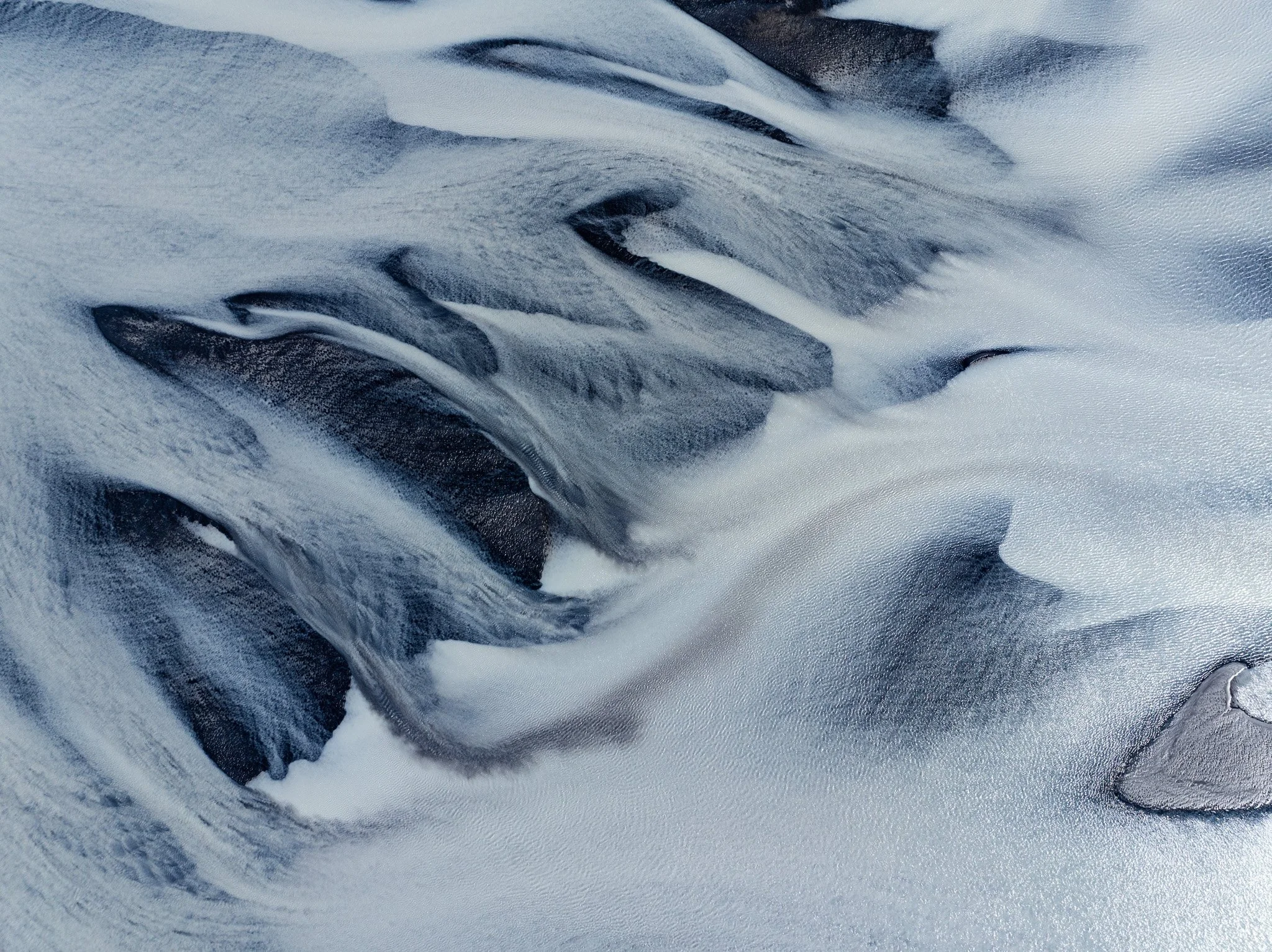 Aerial view of flowing ice and dark crevasses on an Icelandic glacier