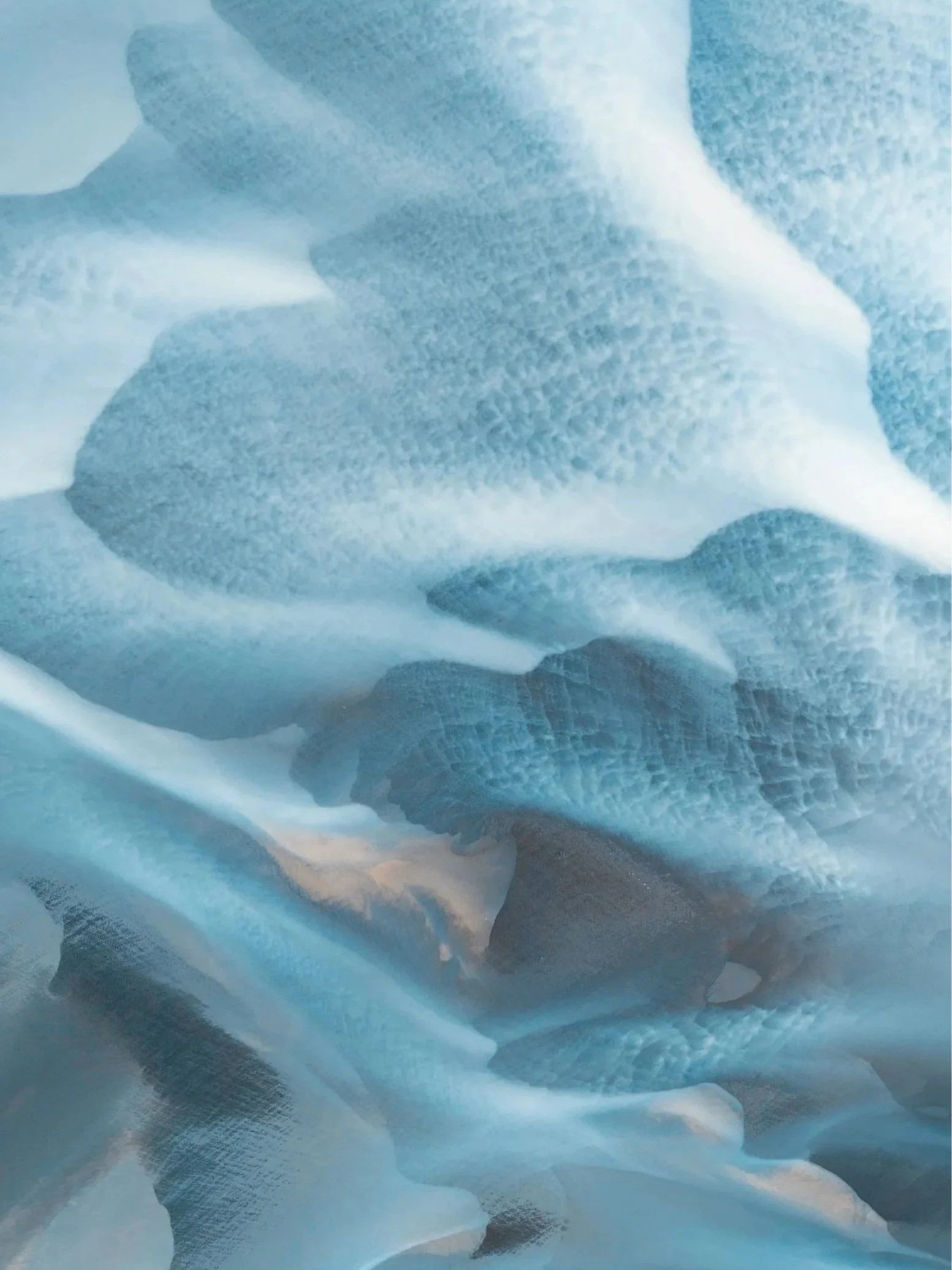 Aerial view of pale blue glacial terrain with flowing natural patterns in Iceland