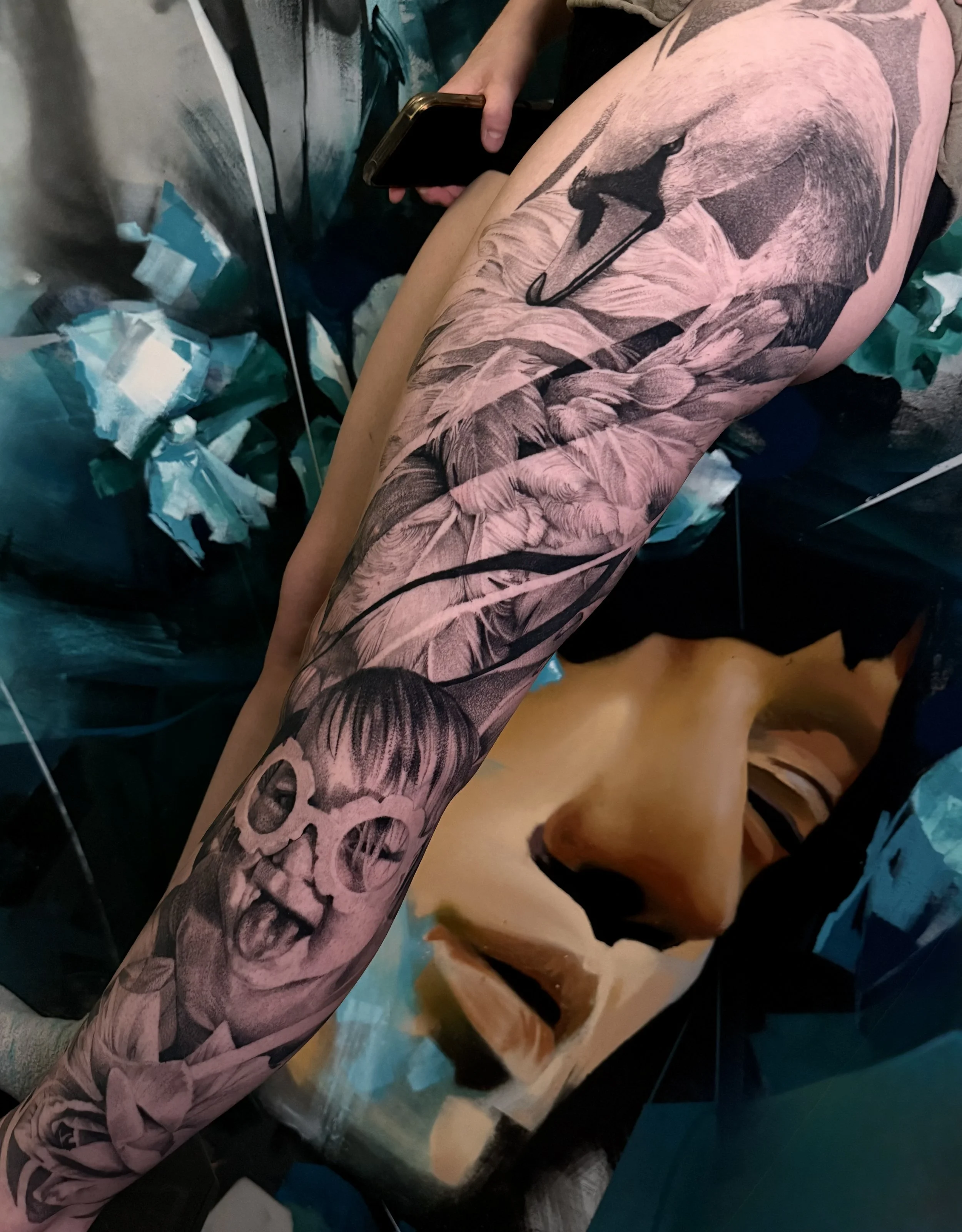 A person with a large detailed tattoo of a swan head and daughter portrait on the entire leg