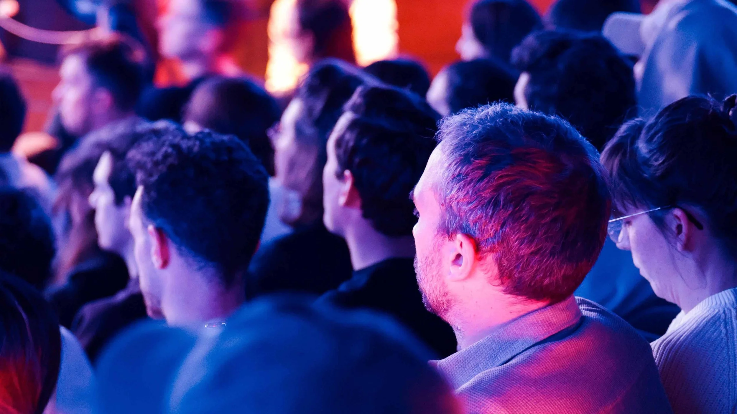Foule de spectateurs réunis dans une salle éclairée de lumières bleues et violettes (événement La Nuit du Trail).