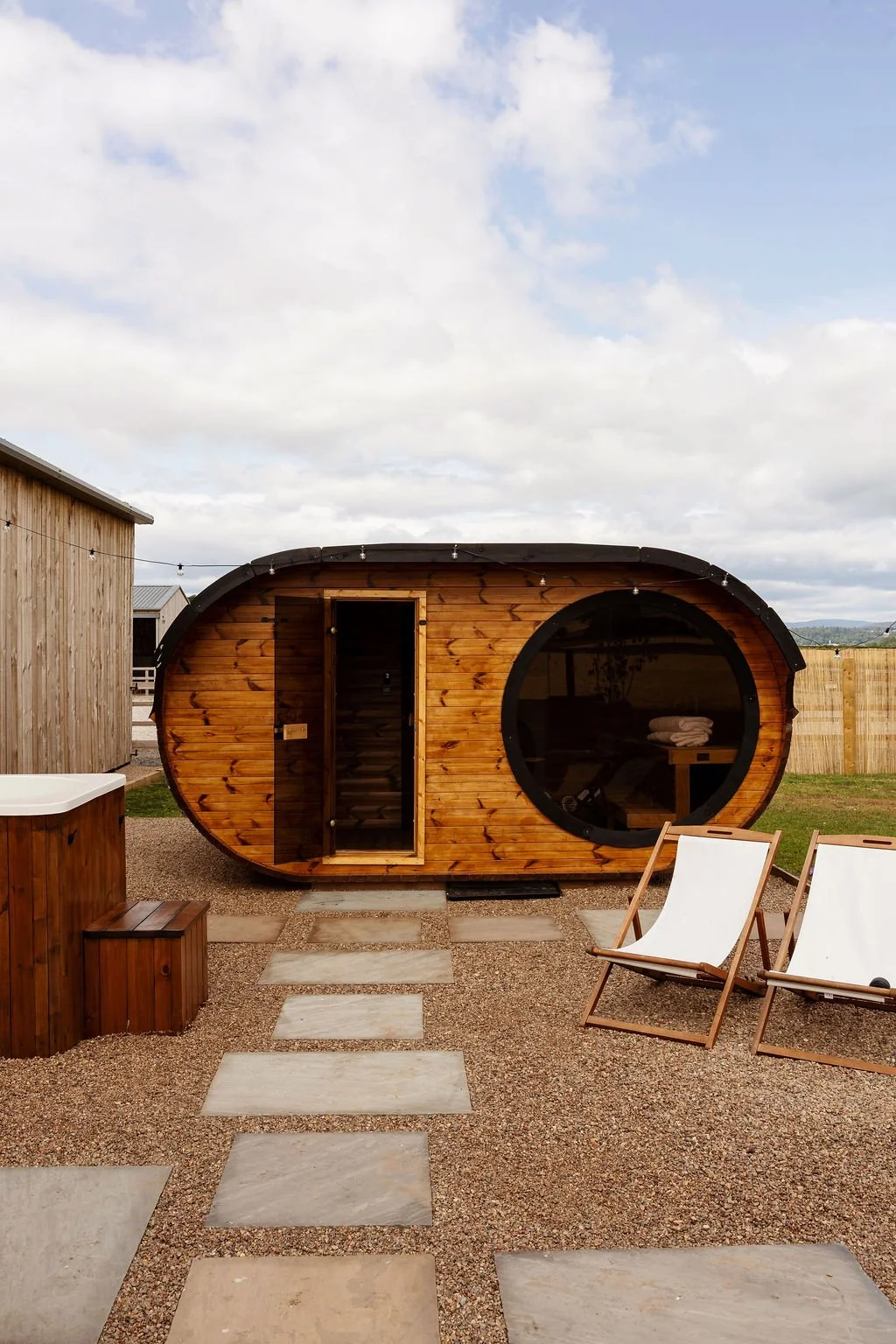 Scandi sauna, decked chairs and cold plunge. Gravel area with paving.