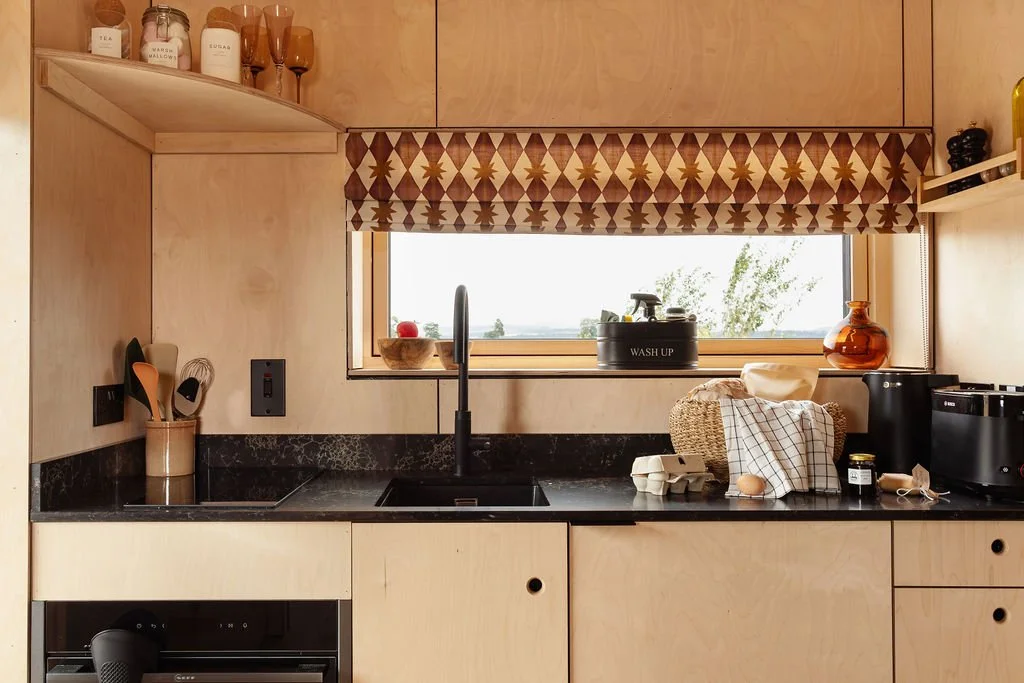 Ply kitchen with black worksurfaces. Ashleigh Mercia blinds. Built in oven. 