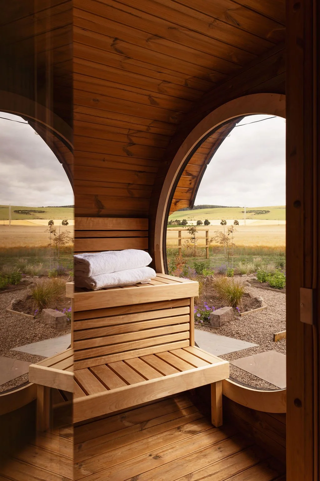 Inside of a timber sauna. seating with towels. Views from large round window.