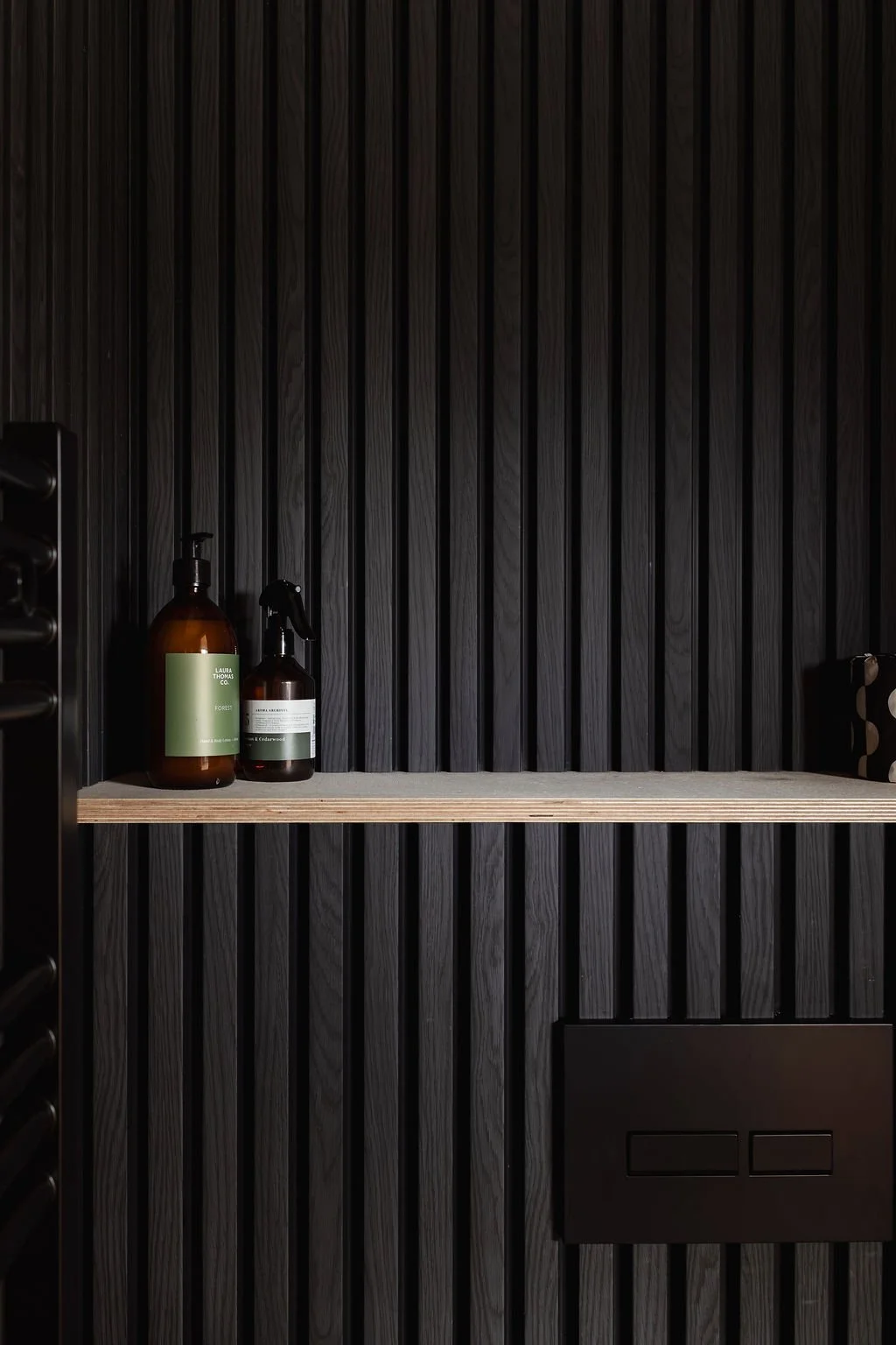 A close up of the nature wall in shower room with toiletries. 