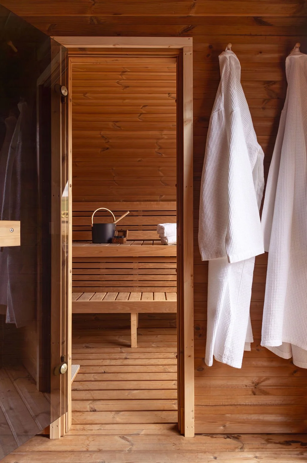 View of sauna from the changing area. Two robes hanging.