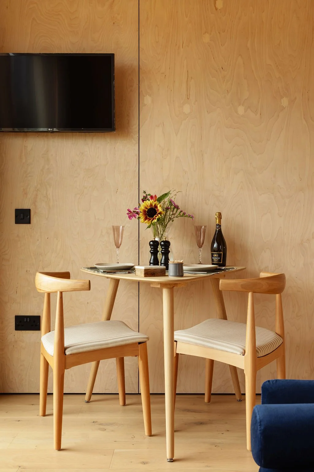 Dining area with wooden table and chairs. TV mounted on wall.