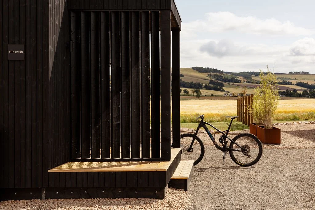 Entrance to the cabin with wooden slats. A bike in a bike rack, with a view beyond.