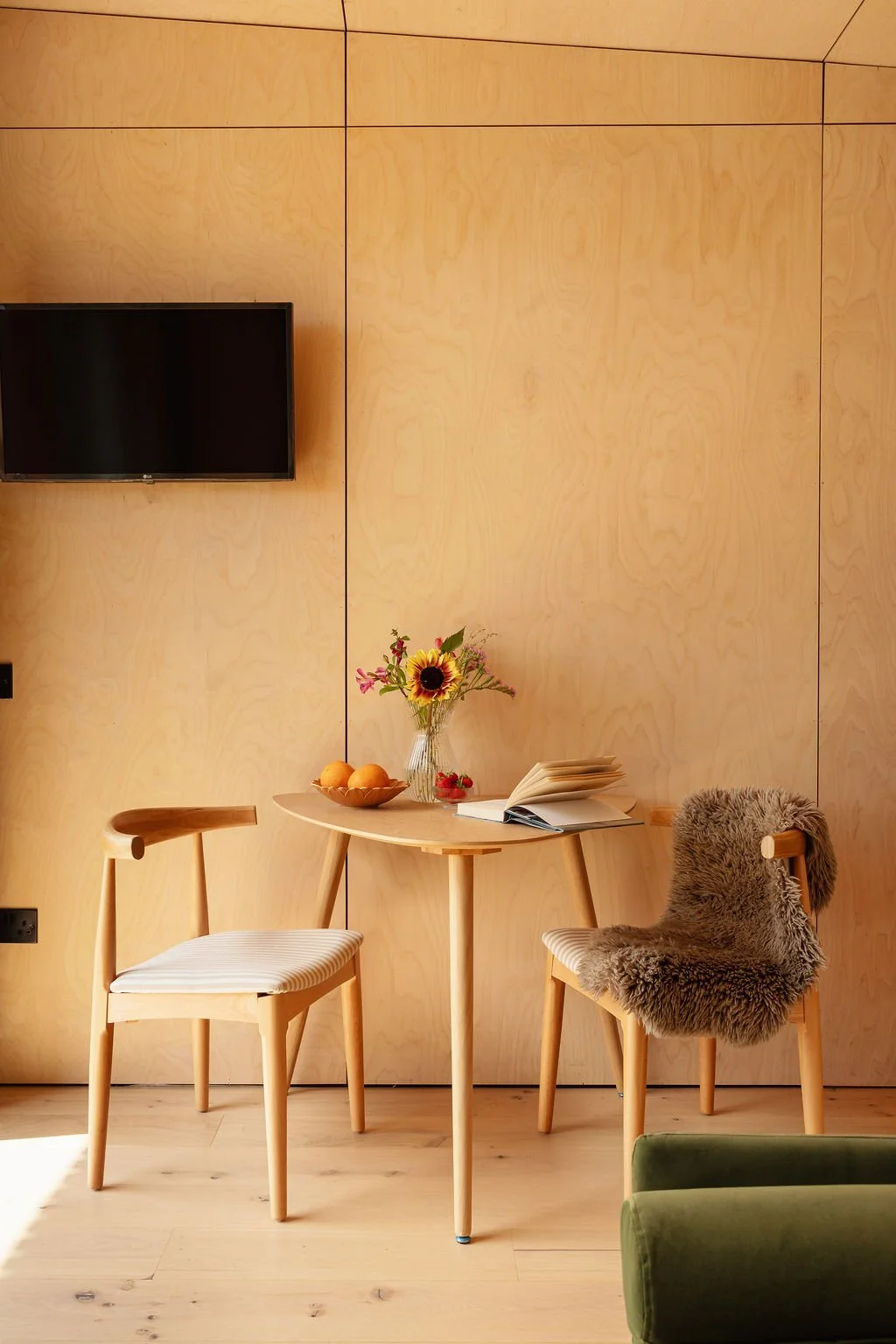 Wooden dining area with two chairs. Ply walls. wooden floors, smart TV wall-mounted.