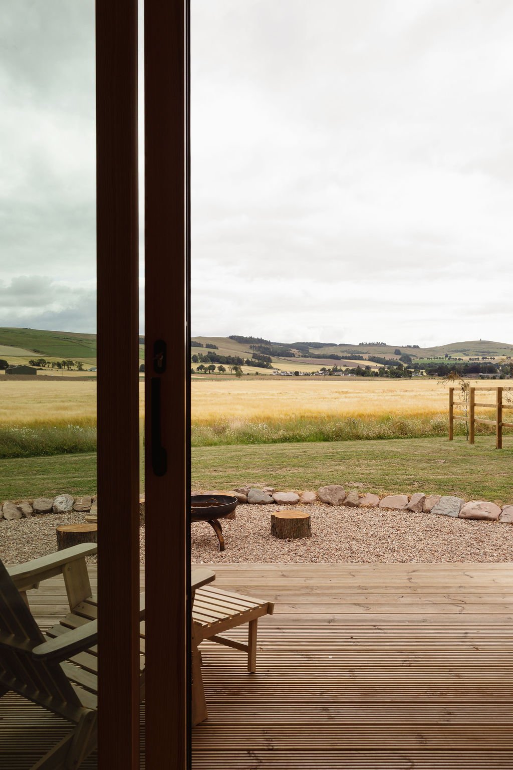 Doors open onto a decked area with farmland view beyond.