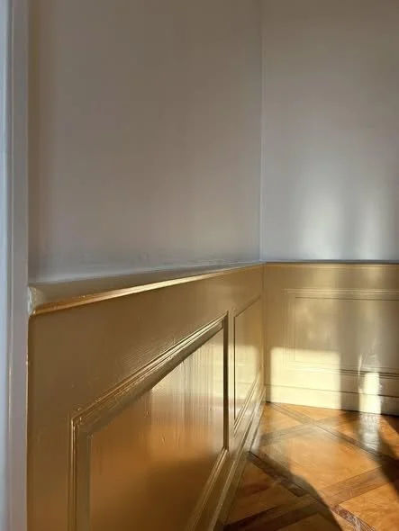 coin de mur avec moulures dorées et parquet en bois