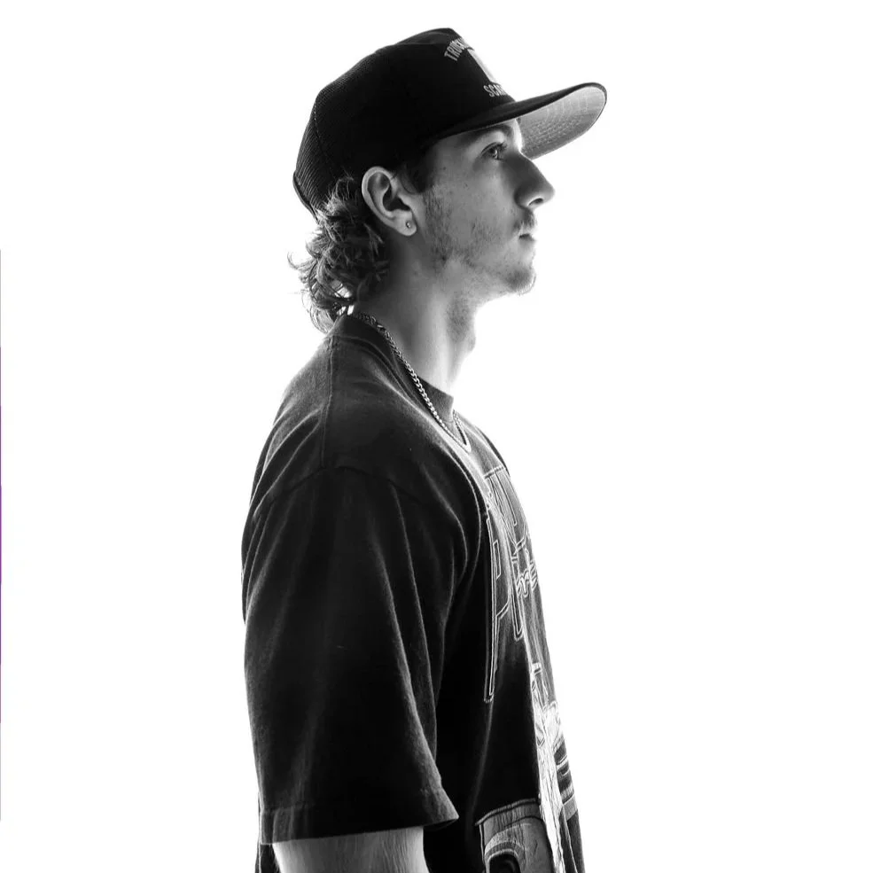 Black and white profile image of a young man wearing a baseball cap and casual t-shirt, looking to the right.