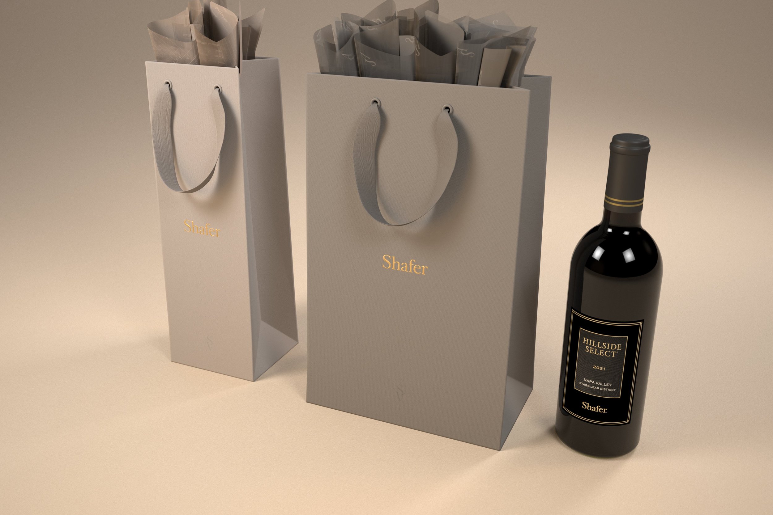 Two white gift bags with gray handles, each with the name 'Shafer' in gold lettering, filled with gray paper, and a bottle of Hillside Select 2021 Napa Valley wine placed next to the right bag on a beige surface with a plain beige background.