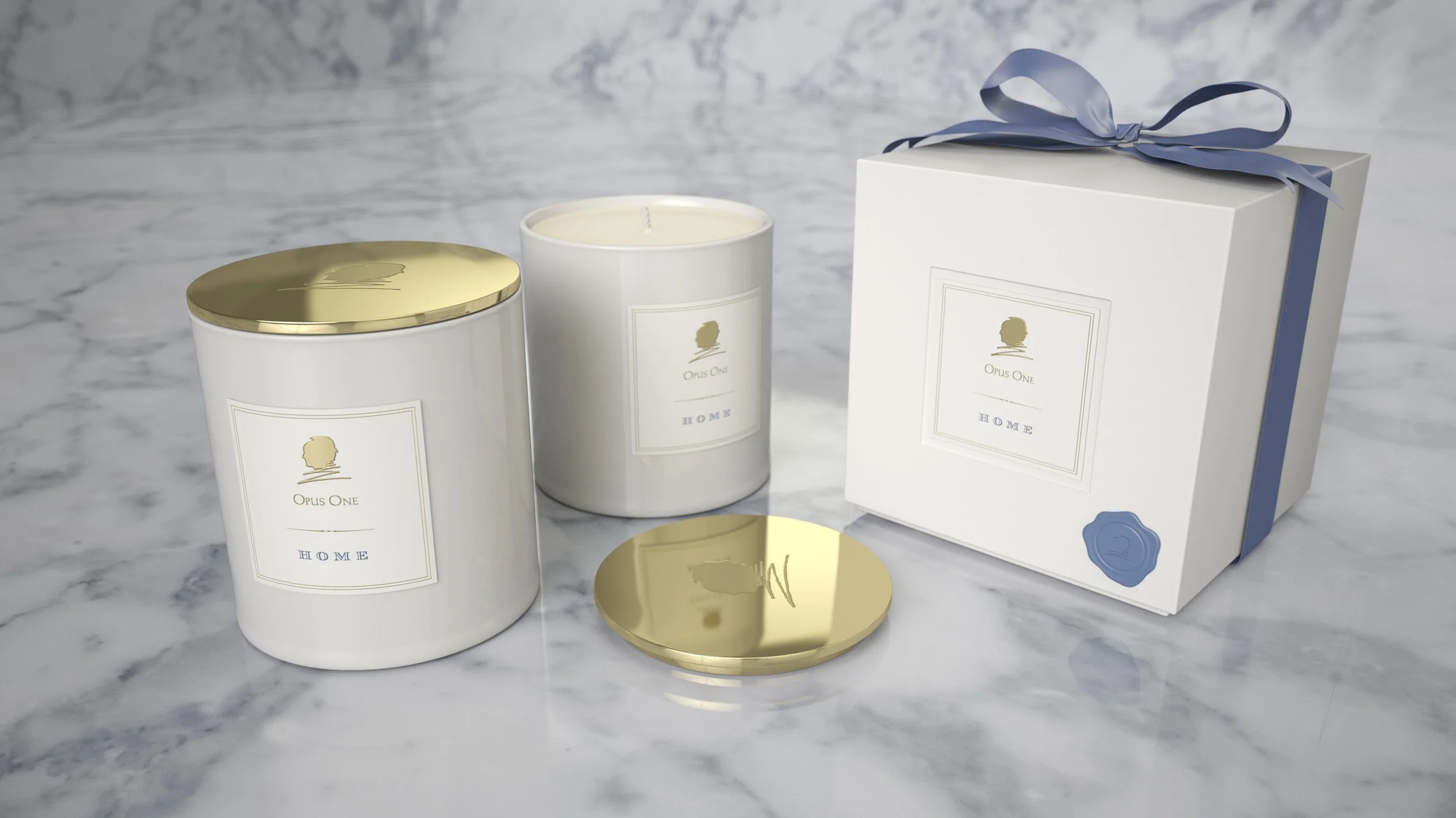 Two white candles and a white gift box with a blue ribbon on a marble surface. The candles and the box have labels reading 'Opus One HOME' with a gold logo of a person's profile.