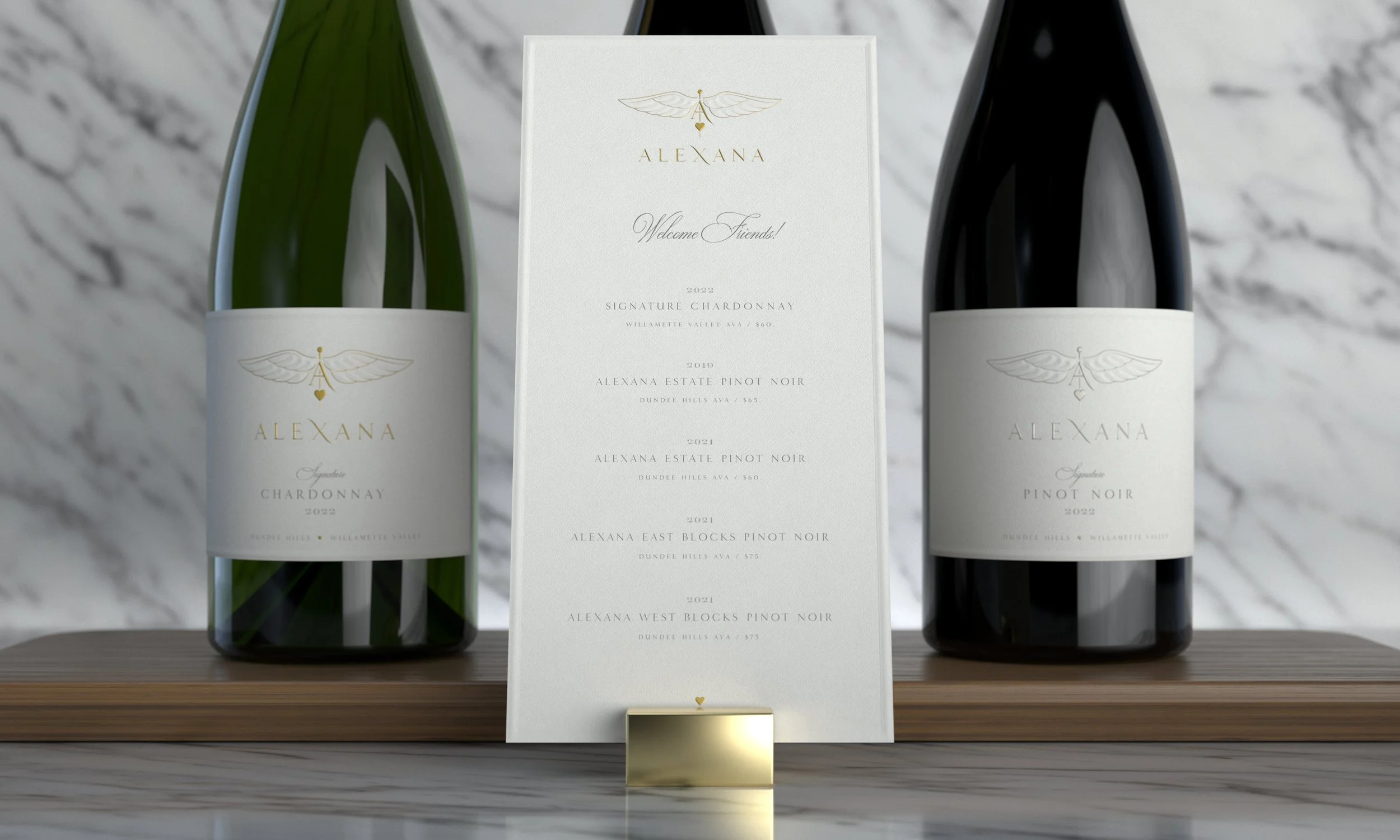 Three bottles of Alexana wine and a white informational display in the middle. The bottles are labeled Chardonnay, Pinot Noir, and West Blocks Pinot Noir, with the middle display listing various wines from the Alexana estate.
