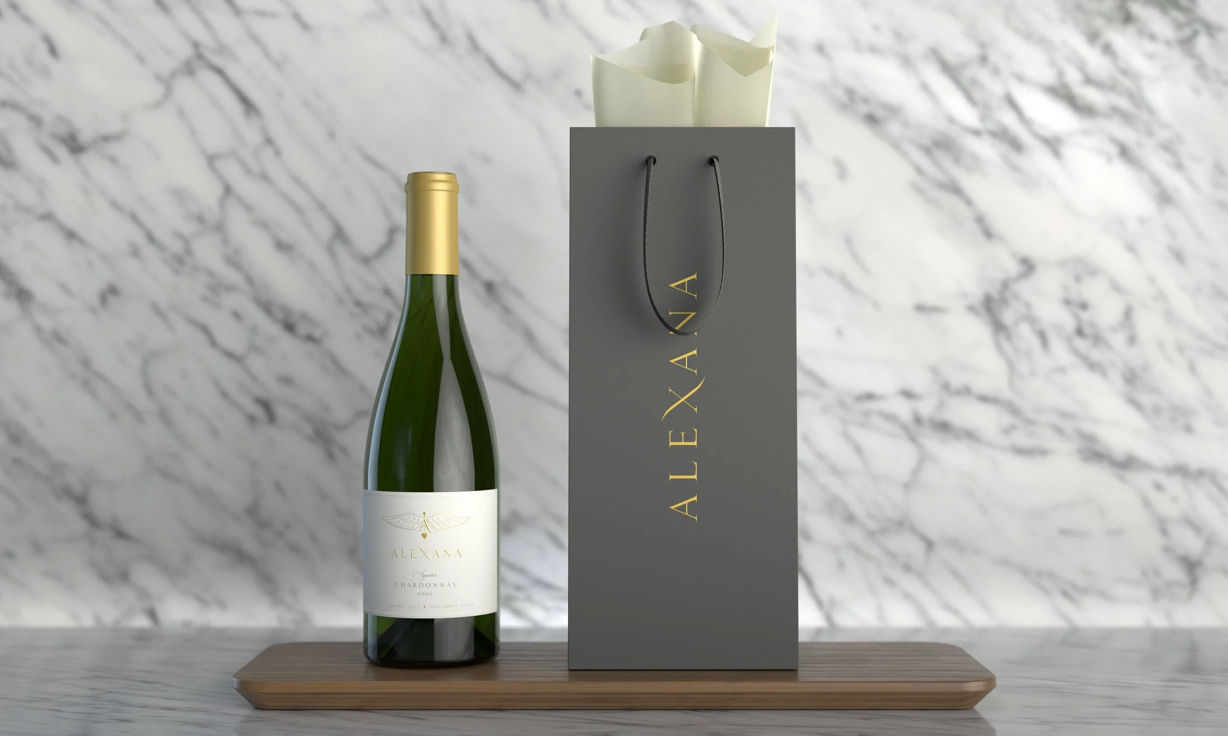 A bottle of Alexana Chardonnay wine on a wooden tray next to a gray Alexana branded box with a handle, in front of a marble background.