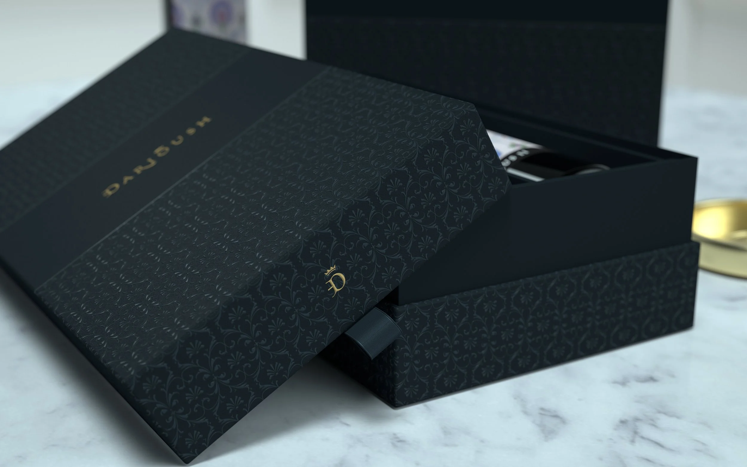 A black cardboard box with gold lettering that reads "D'AUBUSSON". The box features a decorative pattern and is partially open, revealing a watch inside.