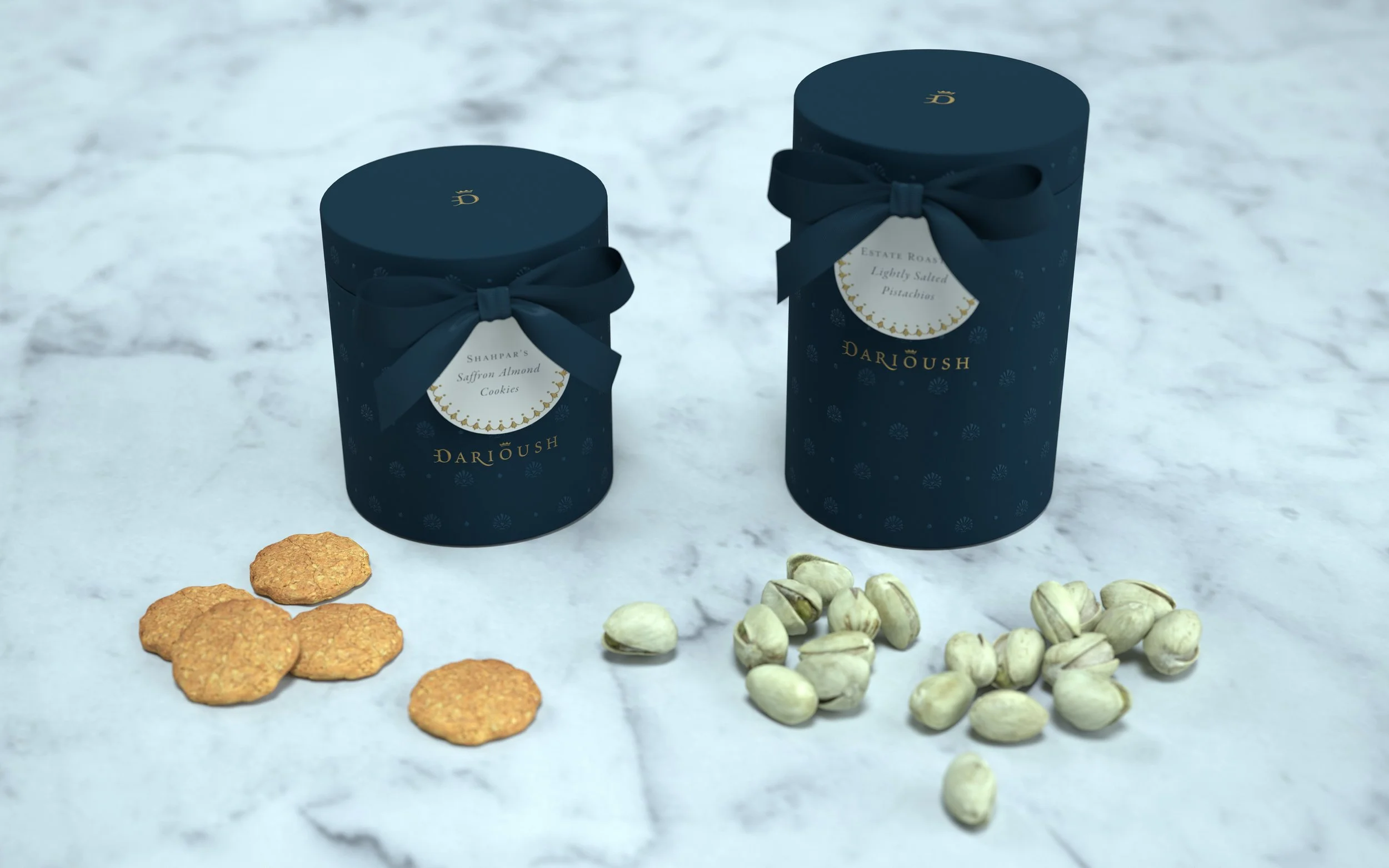 Two navy blue cylindrical boxes with gold lettering and ribbons, labeled 'Shahpar's Saffron Almond Cookies' and 'Estate Roasted Lightly Salted Pistachios,' placed on a white marble surface, with cookies and pistachios arranged in front.