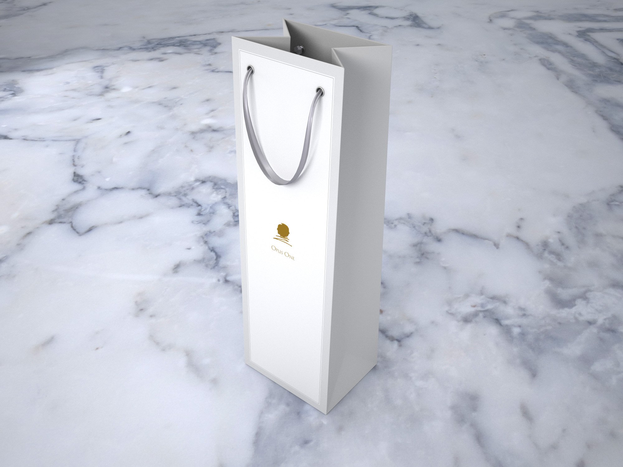White gift bag with a gold logo and gray handles on a snowy surface.