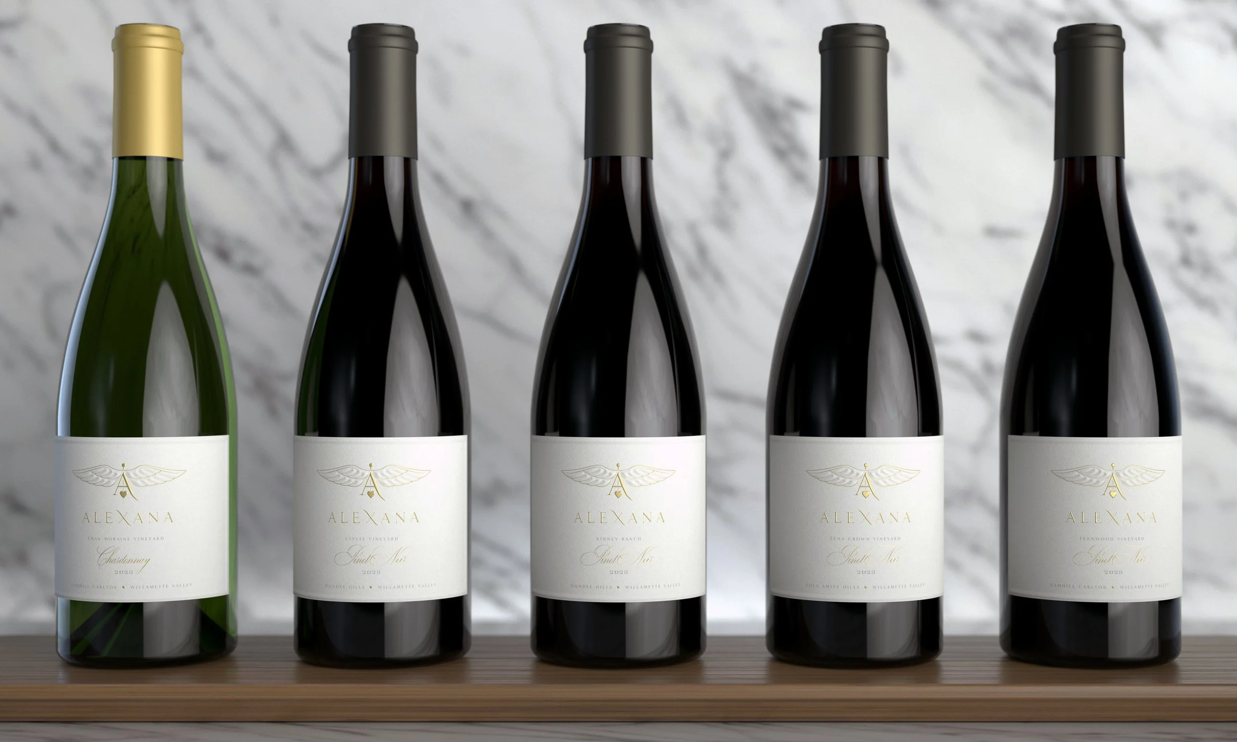 Six wine bottles with white labels and gold, silver, and black foil caps, arranged in a row on a wooden surface against a marble background.