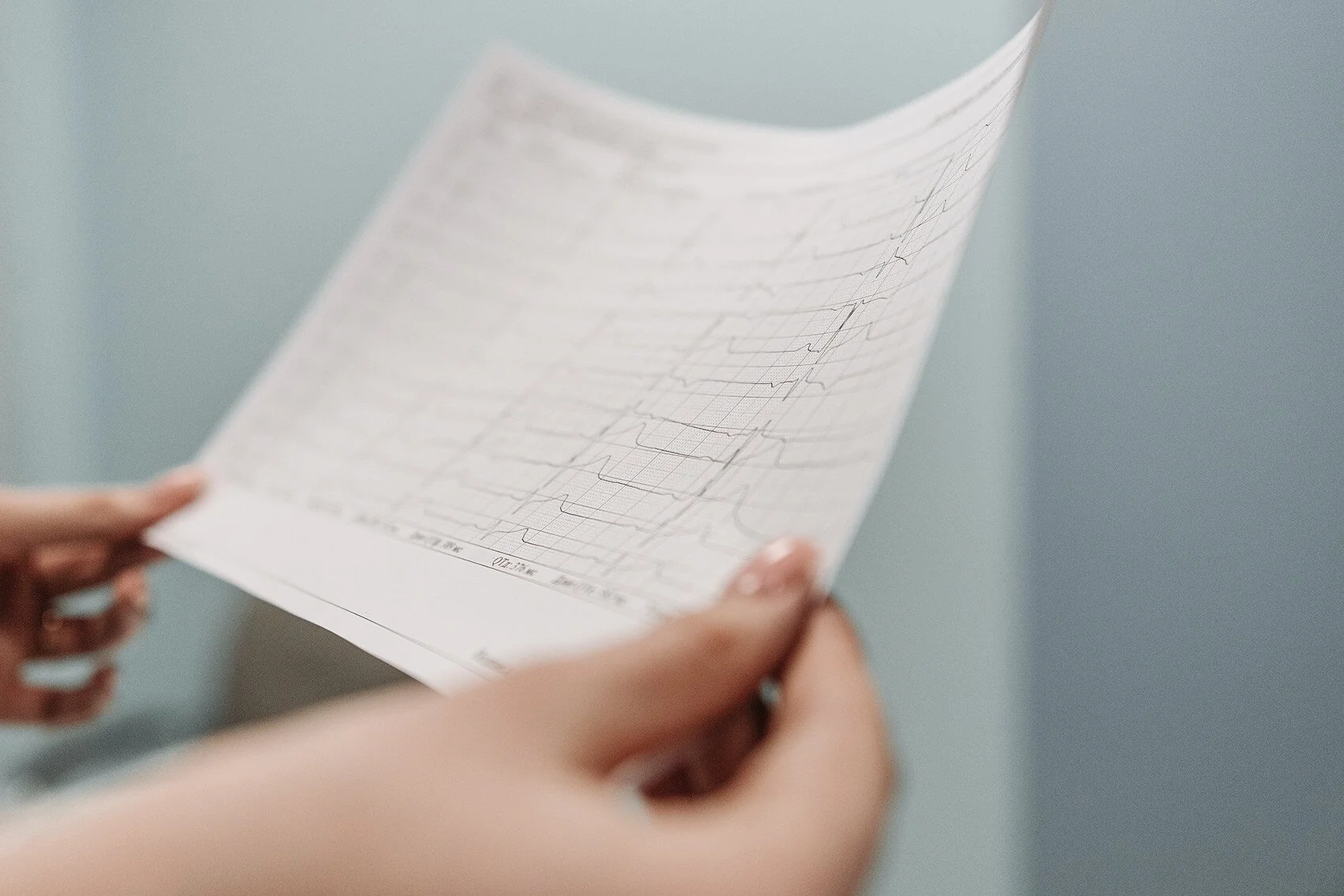 Eine Person hält ein medizinisches EKG-Diagramm, das auf Papier gedruckt ist, und betrachtet es.