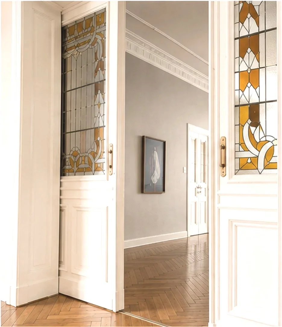 Innenansicht eines mit Stained-Glass-Fenstern geschmückten Flurs in einem eleganten Haus.