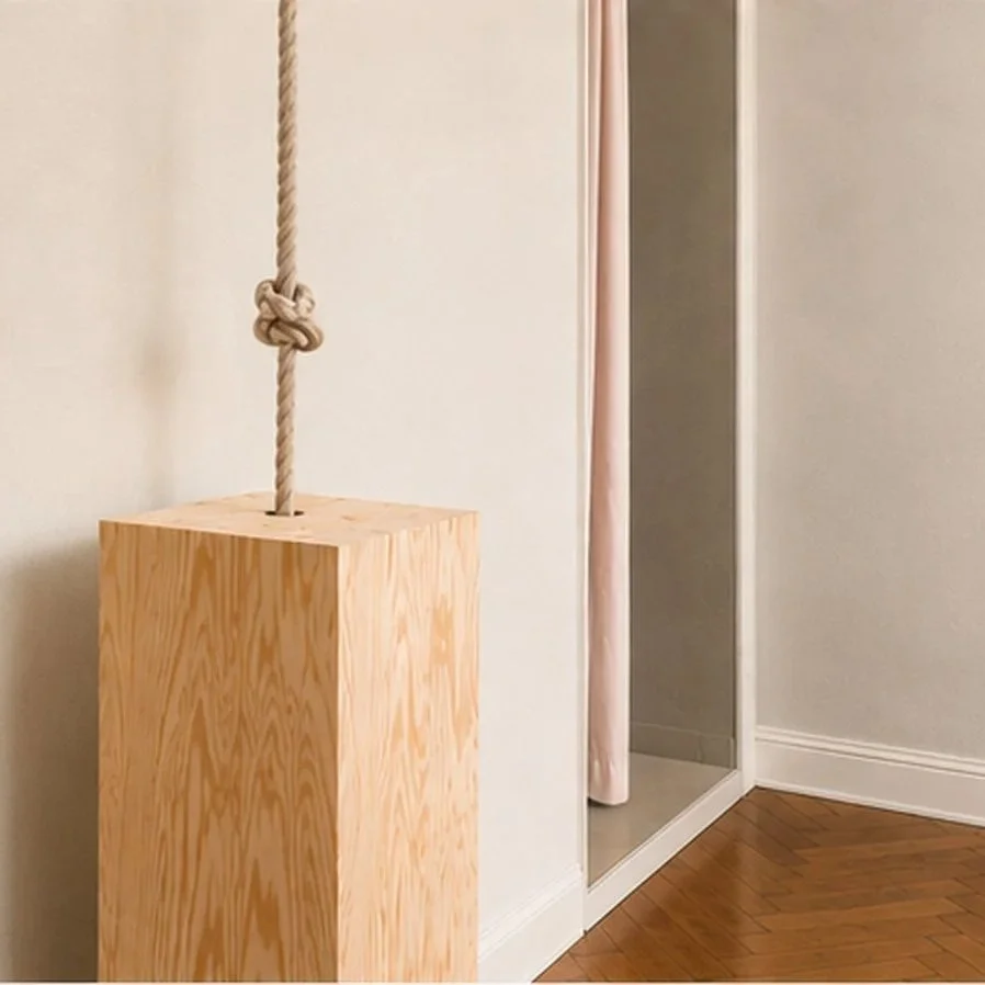 Ein Holzblock mit einer Seilaufhängung hängt an einer Wand in einem Raum mit Holzboden.