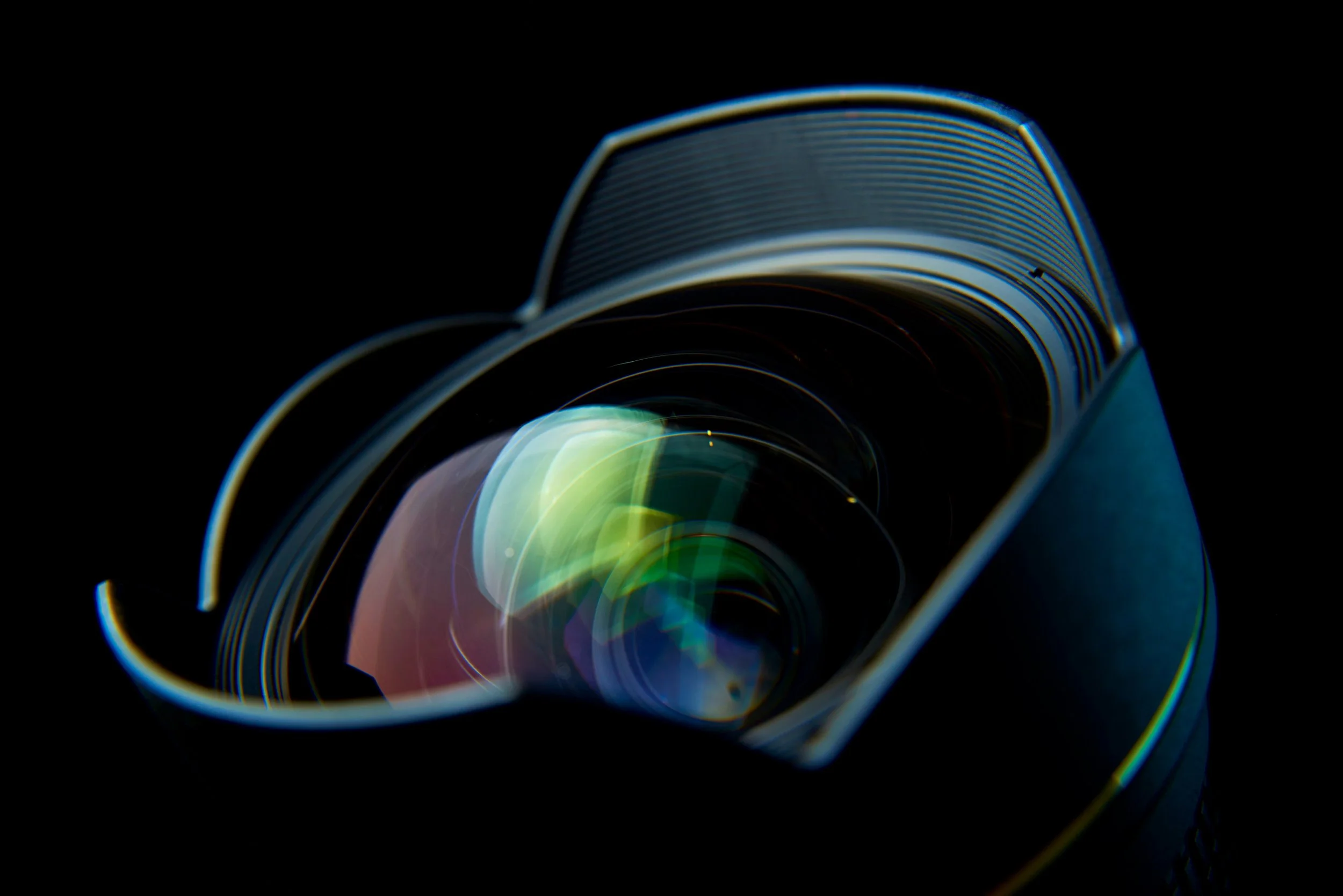 Close-up of camera lens with reflections and an aperture ring, set against a black background.