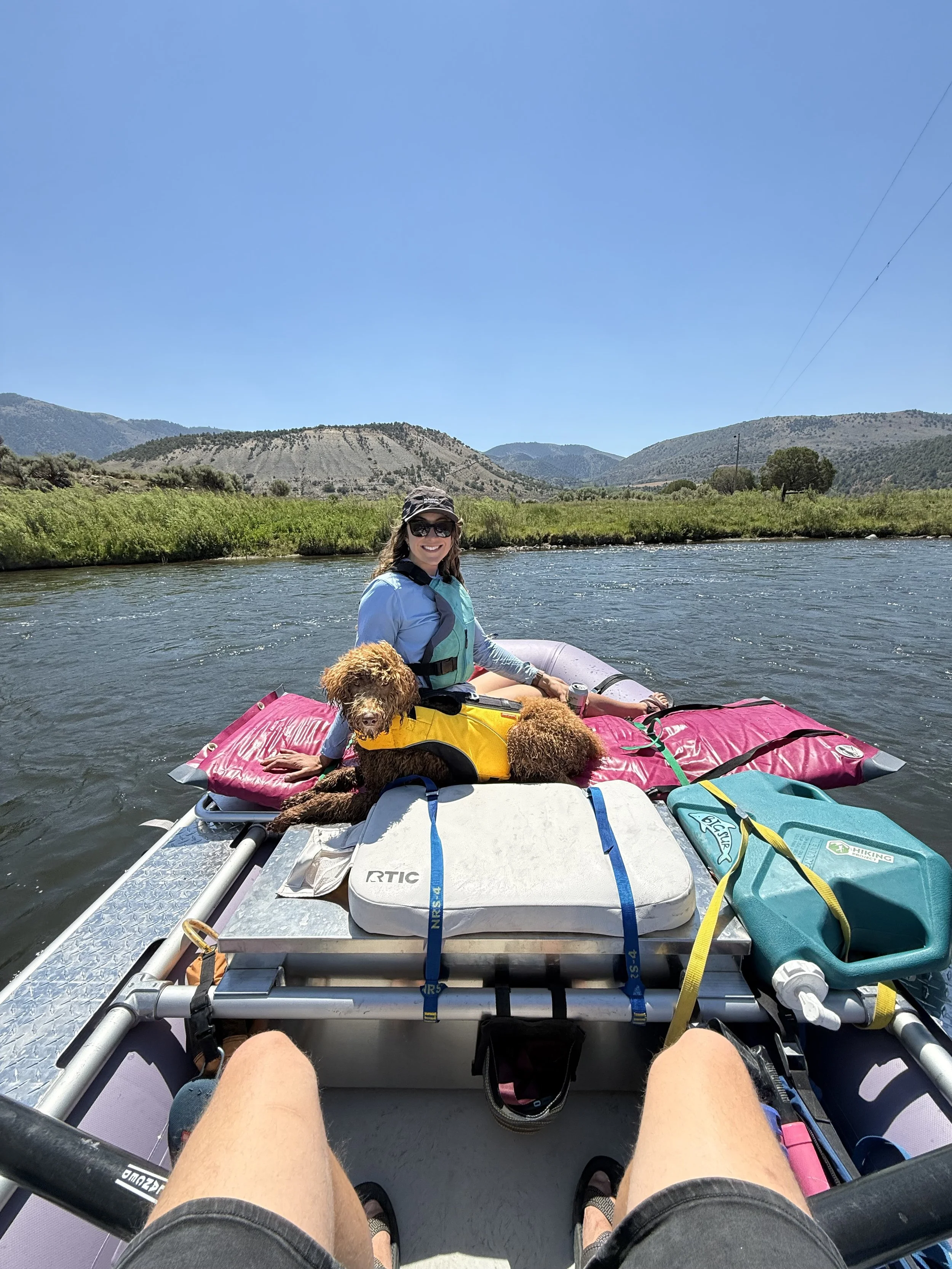 Stephanie Hands rafting with a dog on a river surrounded by Colorado mountains.