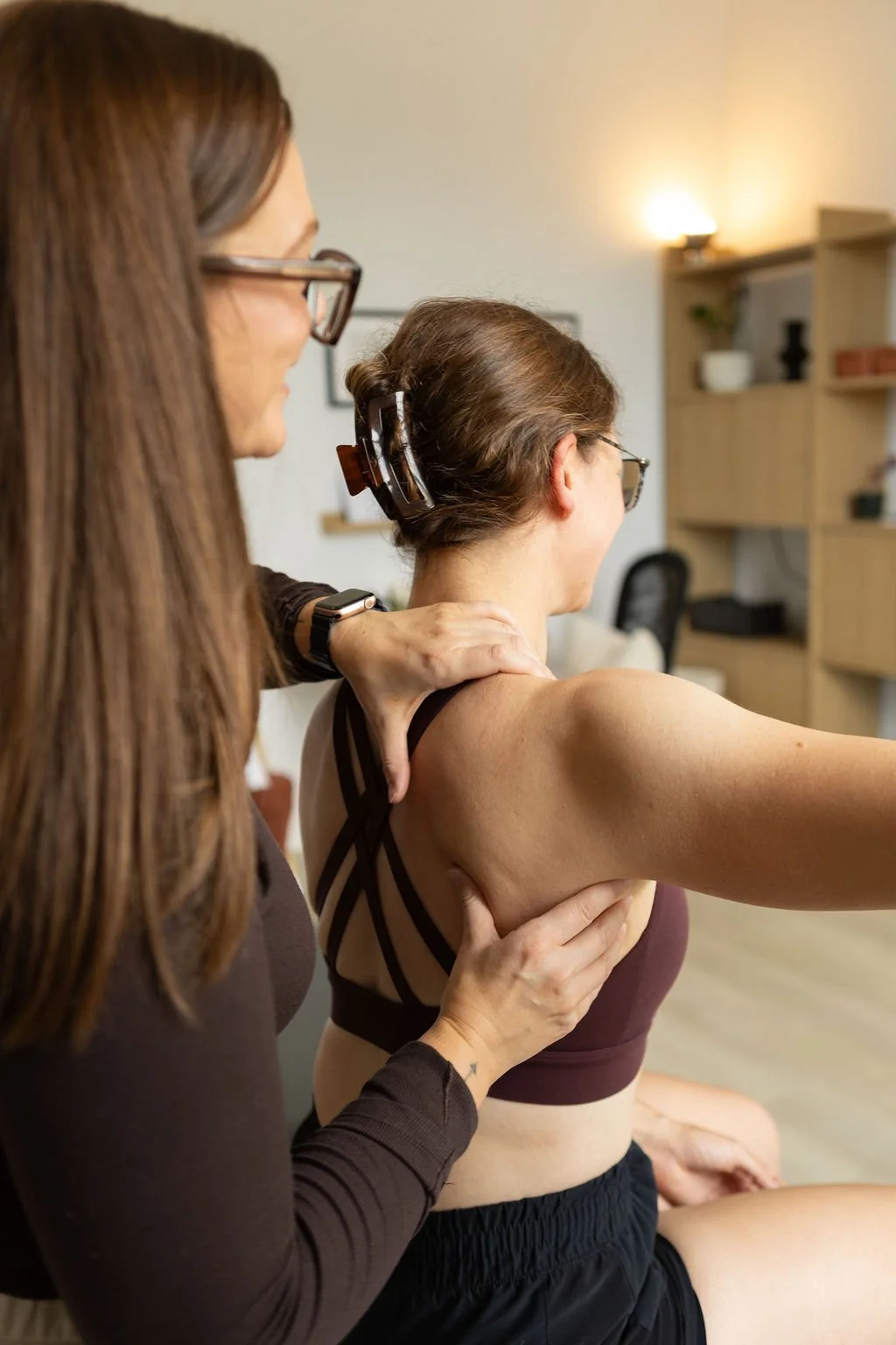 A woman receiving physiotherapy treatment for her shoulder from another woman (physiotherapist) in a clinical setting.