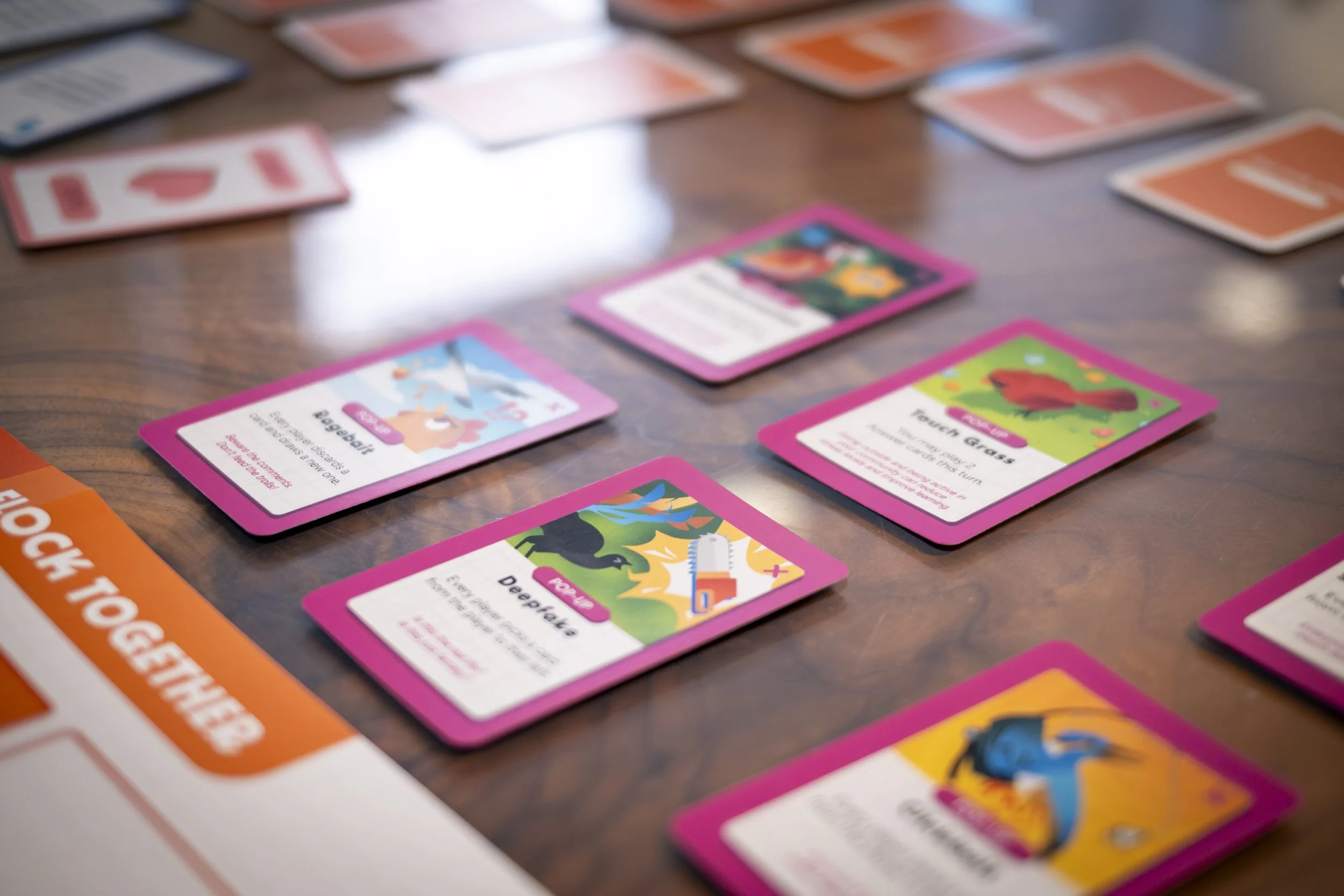 Colorful educational game cards on a wooden table, featuring illustrations and text for different school grades and activities.
