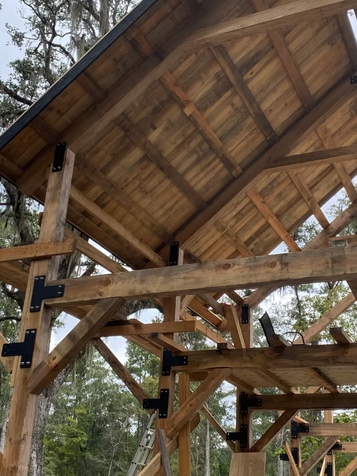 Under construction wooden building framework with exposed beams and roof structure.