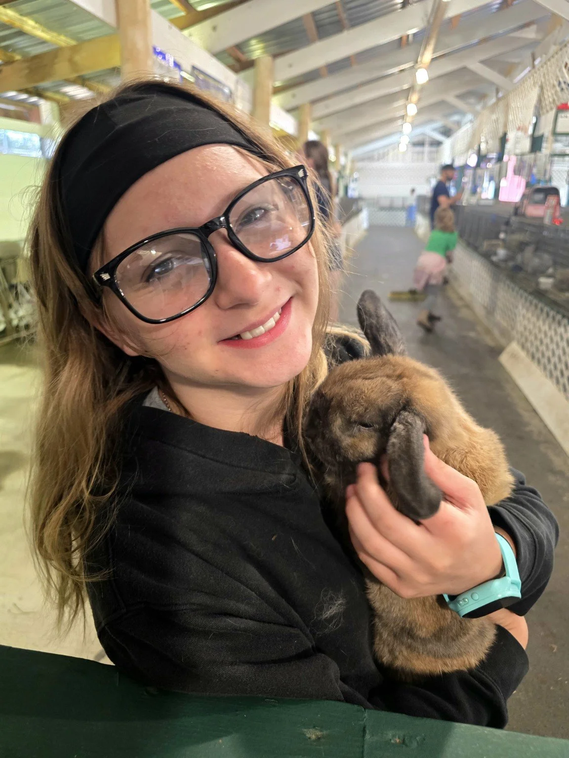 Promise Path Farm family member holding a brown lop rabbit at a local fair.